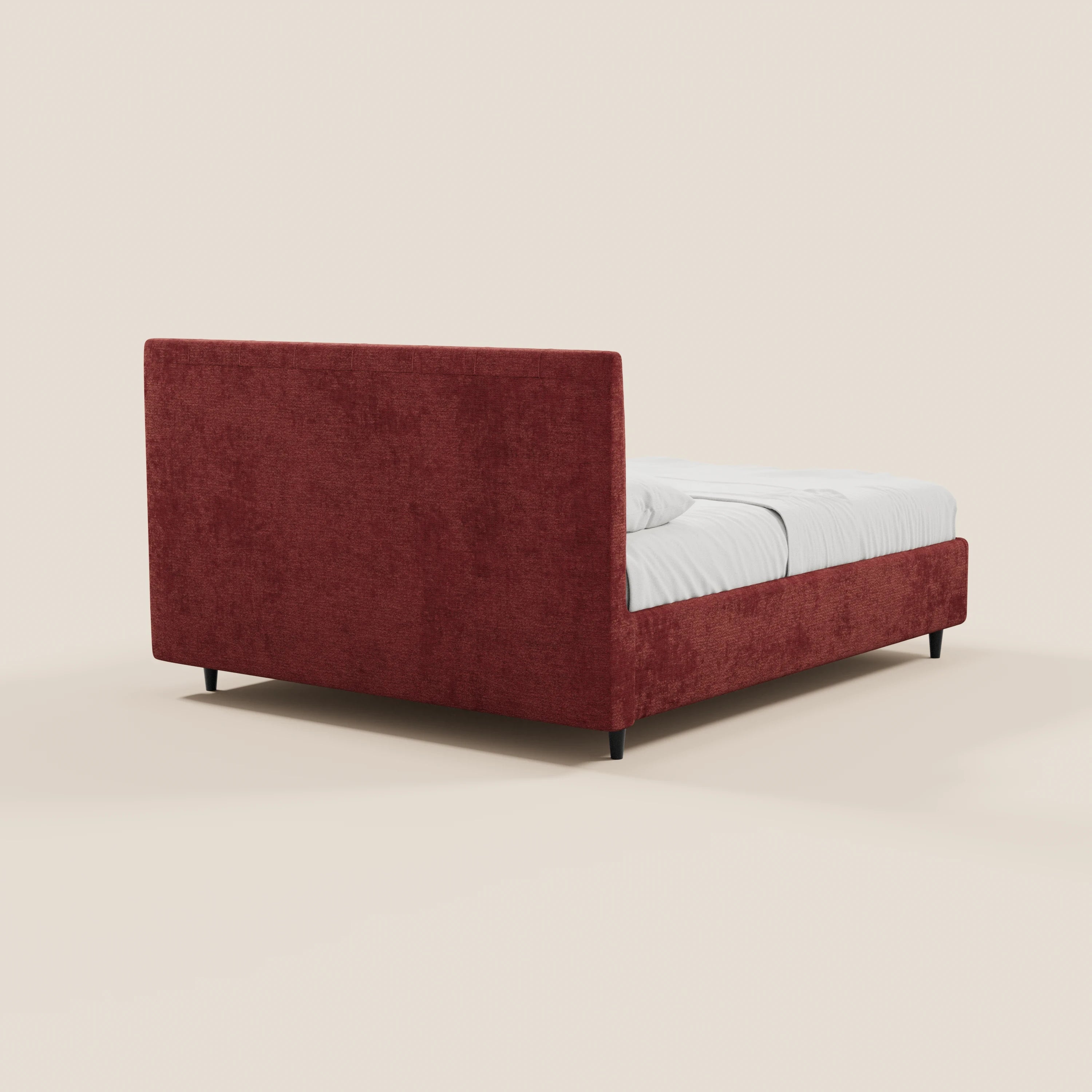 Il letto imbottito ONYX di Letti.store presenta una testiera verticale rettangolare in tessuto certificato Oeko-Tex®, una struttura in tessuto rosso intenso, piedini corti neri e un vano contenitore. Immagine vista da dietro a sinistra con biancheria bianca su sfondo chiaro.