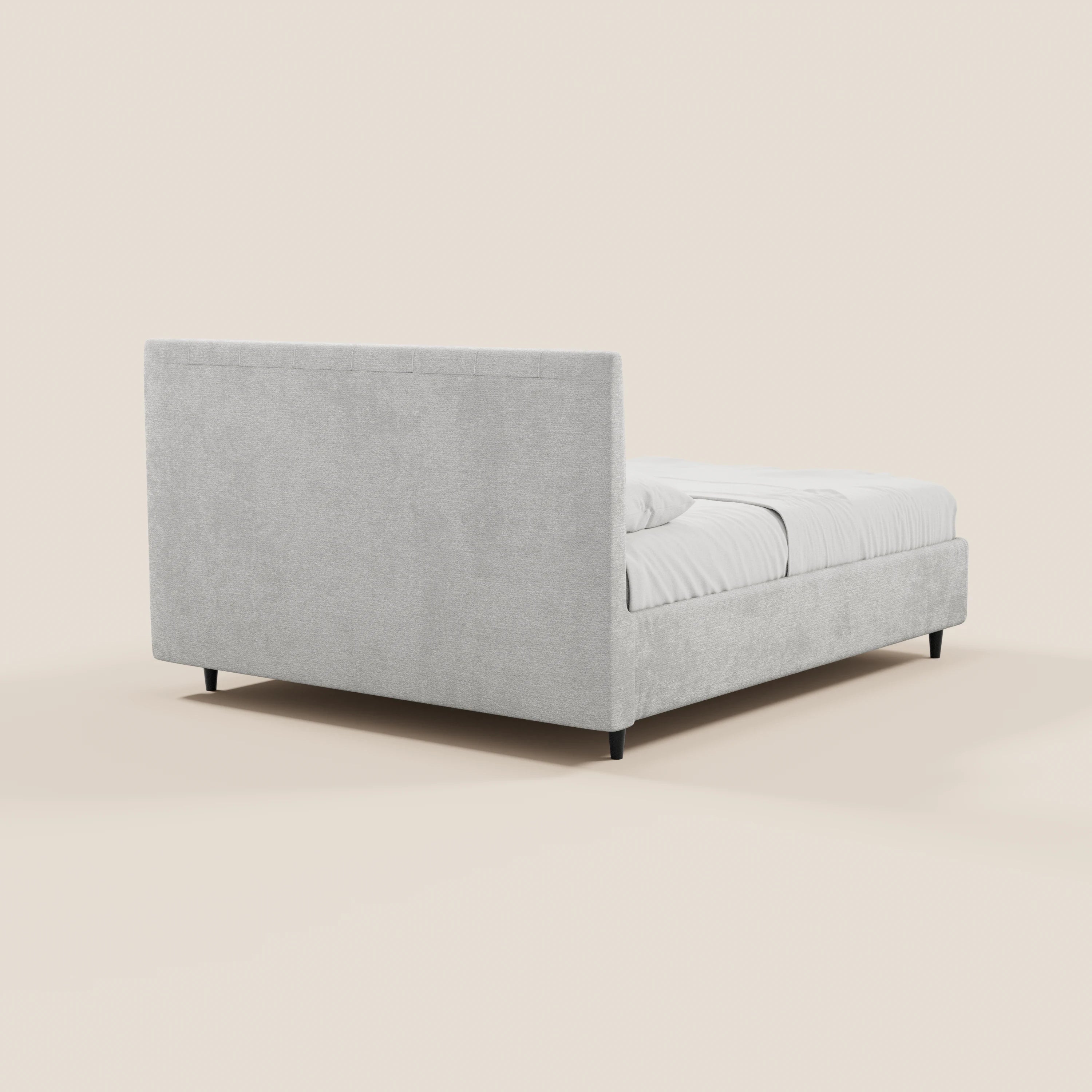 Il letto imbottito ONYX con contenitore e testiera verticale in tessuto Oeko-Tex® di Letti.store è raffigurato in una prospettiva angolata dal retro e di lato, con rivestimento grigio chiaro, gambe nere, biancheria da letto bianca e una testiera alta e imbottita su uno sfondo beige.
