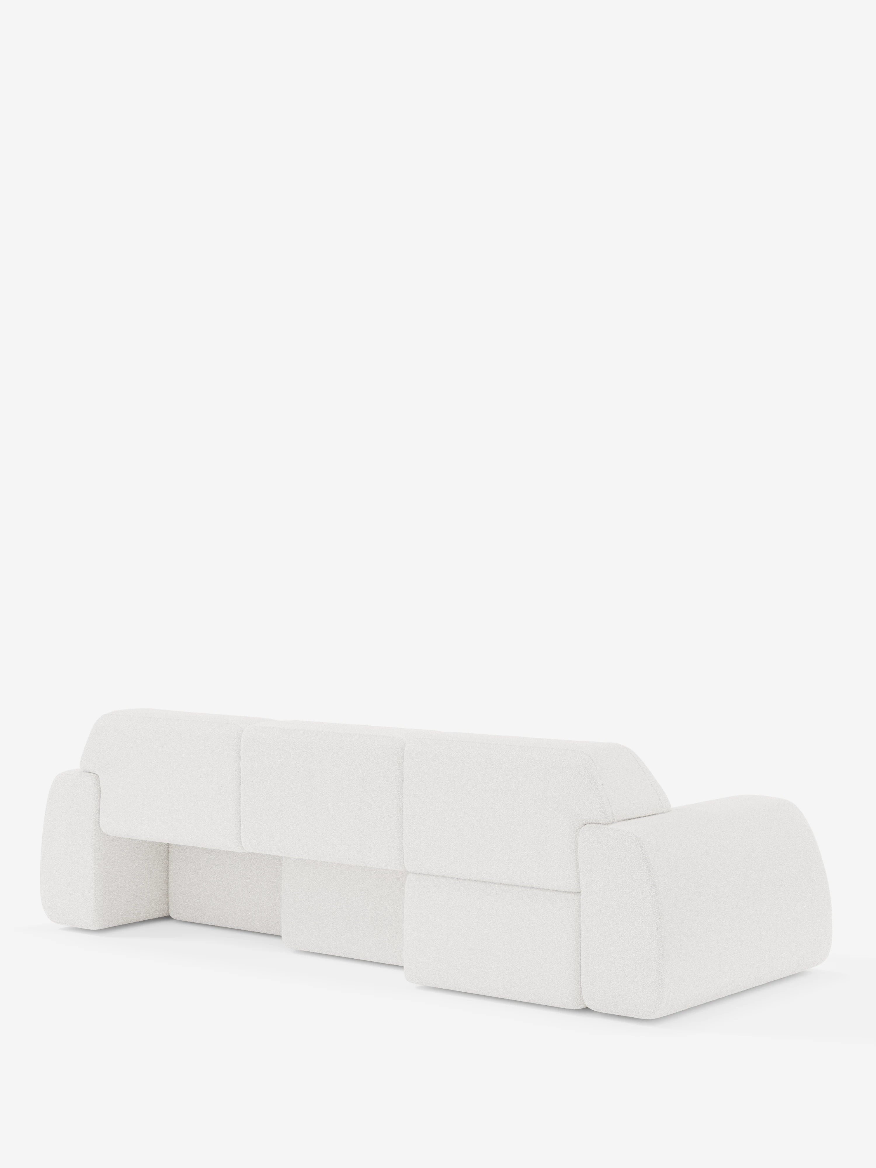 Un divano bianco, minimalista e moderno, con bordi morbidi e arrotondati e cuscini squadrati — visto da dietro — è messo in risalto su una superficie bianca contro uno sfondo bianco a tinta unita, che ne esalta il design pulito e contemporaneo. Si tratta del divano angolare Orbit con penisola reversibile e tutte le sedute allungabili in tessuto smacchiabile effetto cotone T33 di Divani.Store.