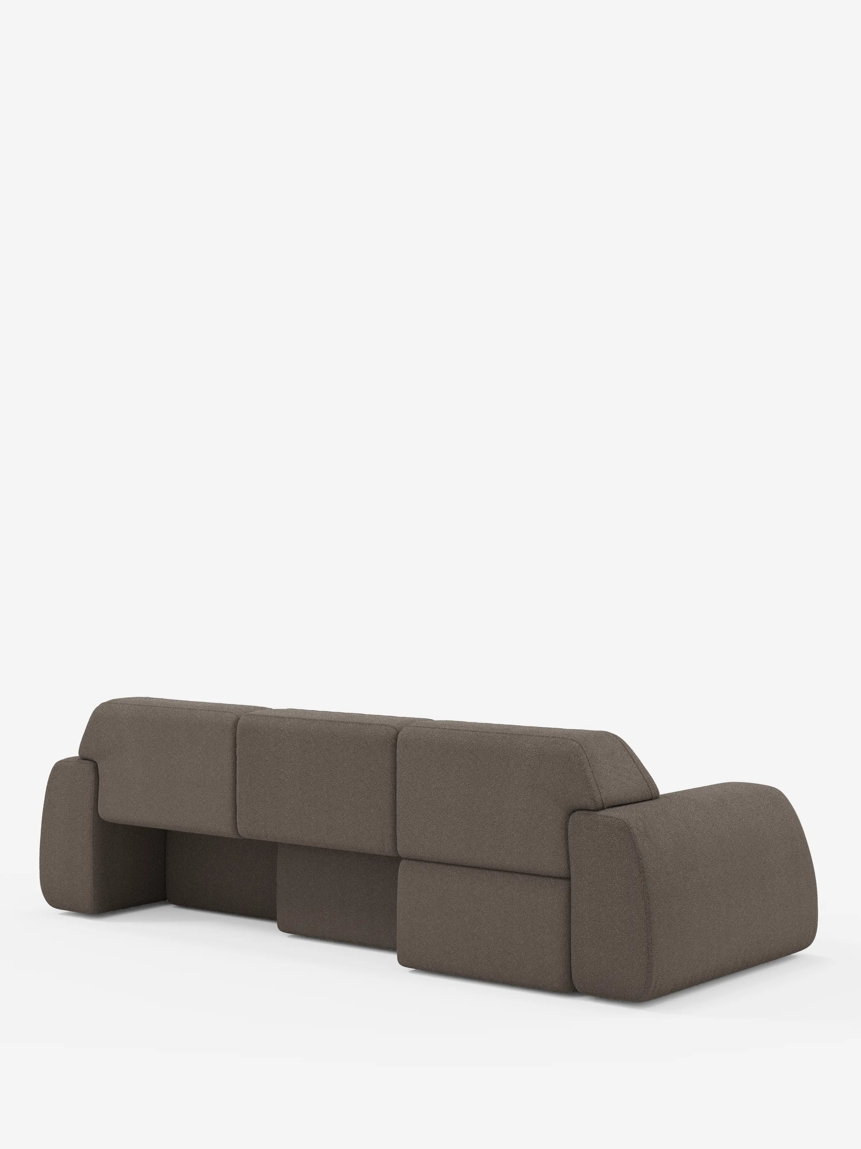 Un divano marrone contemporaneo e modulare — l’Orbit Divano angolare con penisola reversibile e tutte le sedute allungabili in tessuto smacchiabile effetto cotone T33 di Divani.Store — è ripreso di retro su uno sfondo bianco. Questo «divano modulare» di alta gamma presenta tre sezioni di seduta, ampi braccioli a blocco e bordi arrotondati che gli conferiscono un aspetto morbido e geometrico.