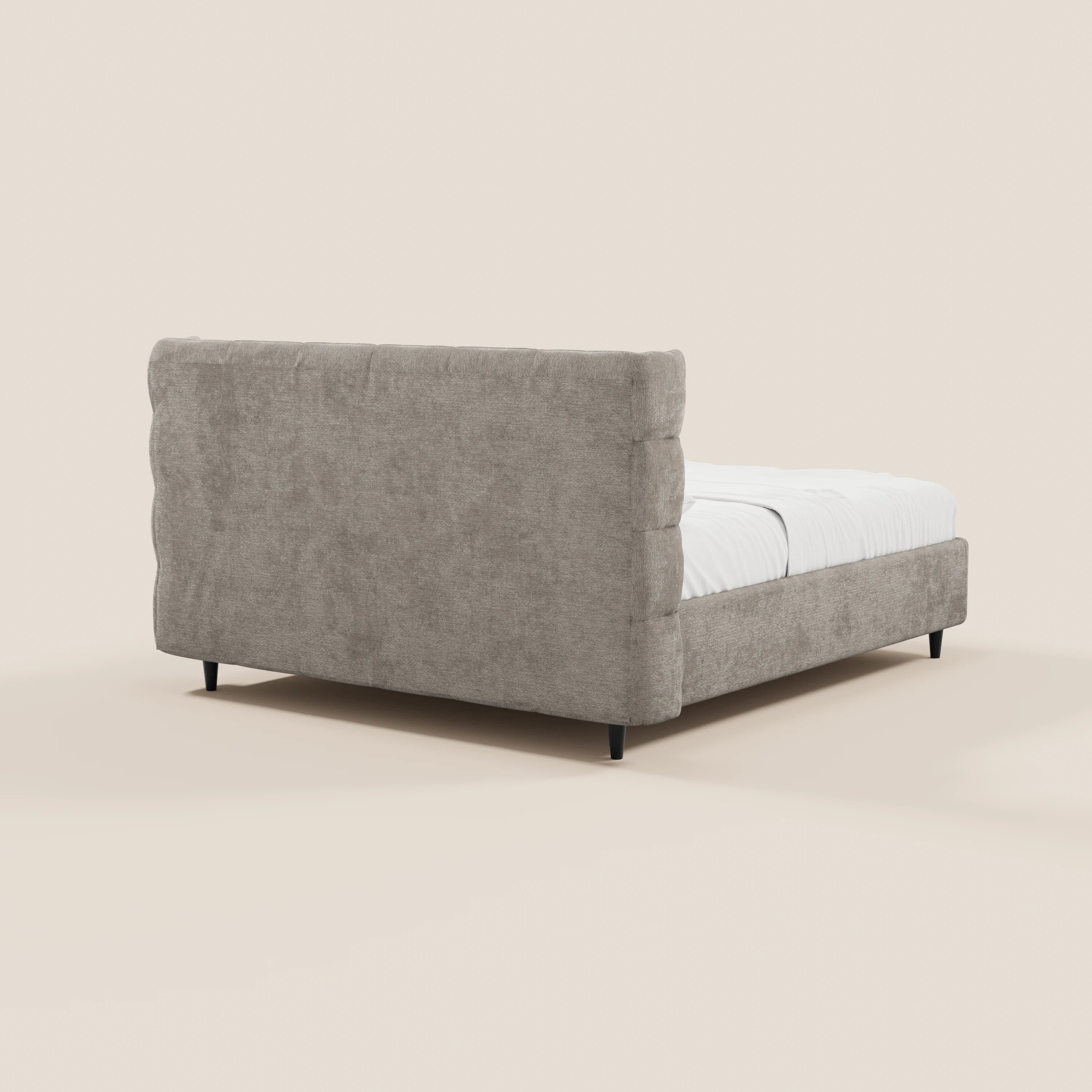 Il letto imbottito RAGNAR di Letti.store presenta una testiera alta capitonné e una base contenitore in elegante tessuto beige chiaro certificato Oeko-Tex®, abbinate a gambe angolate nere e biancheria da letto bianca; il modello è raffigurato nella vista posteriore sinistra su uno sfondo beige a tinta unita.