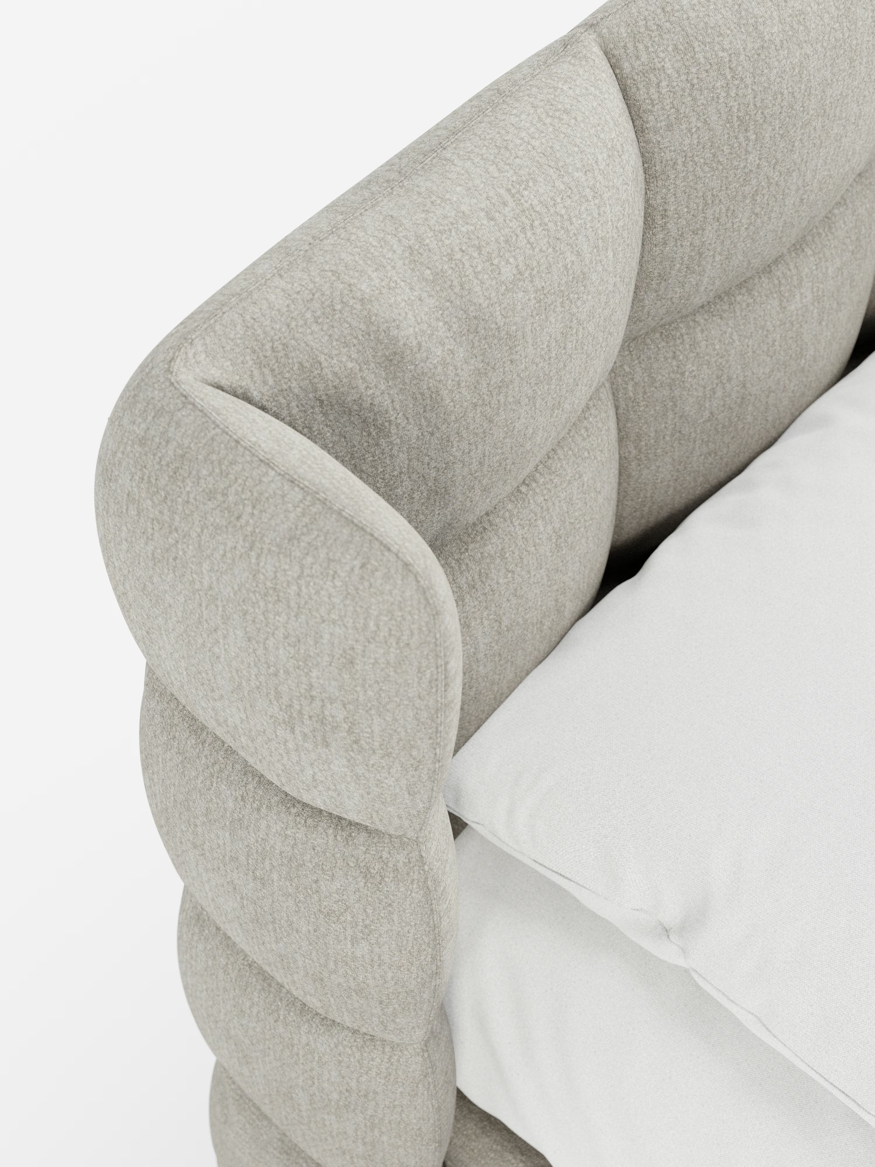 Primo piano del letto imbottito RAGNAR con contenitore e testiera capitonné avvolgente di Letti.store, che mette in risalto il suo morbido rivestimento beige chiaro certificato Oeko-Tex® e i bordi della testiera leggermente arrotondati e trapuntati. L'elegante cuscino di seduta presenta cuciture a vista che ne esaltano l'aspetto accogliente e sofisticato sullo sfondo bianco a tinta unita.