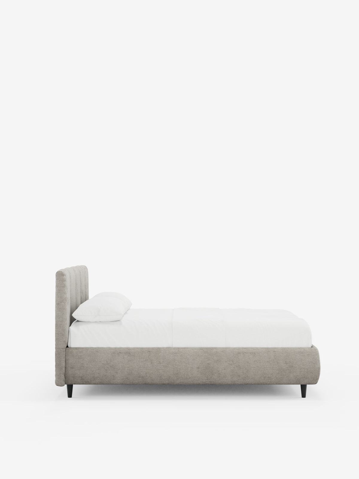 Vista laterale del letto imbottito ARKAM con contenitore e testiera a lavorazione verticale di Letti.store, caratterizzato da una testiera imbottita grigio chiaro certificata Oeko-Tex® e da una struttura in stile shabby chic. Il letto è adornato da un cuscino bianco e da biancheria da letto bianca, presenta gambe corte nere ed è posizionato su uno sfondo bianco a tinta unita.