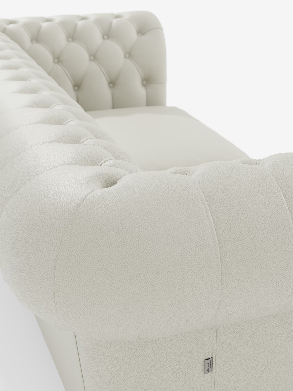 Primo piano del Chester – Divano Chesterfield in vera pelle spessorata a 2 e 3 posti di Divani.Store, caratterizzato da una finitura in pelle bianca trapuntata con braccioli arrotondati e superficie testurizzata. Lo schienale e i braccioli a vista presentano dettagli trapuntati con bottoni e cuciture raffinate. Realizzato come divano artigianale italiano (Made in Italy) e rivestito in vera pelle pieno fiore di alta qualità, il design lussuoso e classico di questo modello risalta sullo sfondo bianco a tinta