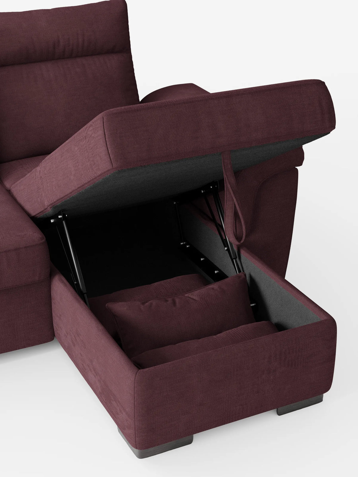 Un divano letto angolare Ischia color prugna scuro con schienali scorrevoli, elemento estraibile e penisola contenitore, con la chaise longue sollevata per rivelare lo spazio di stivaggio interno, un cuscino coordinato e un meccanismo in metallo nero.