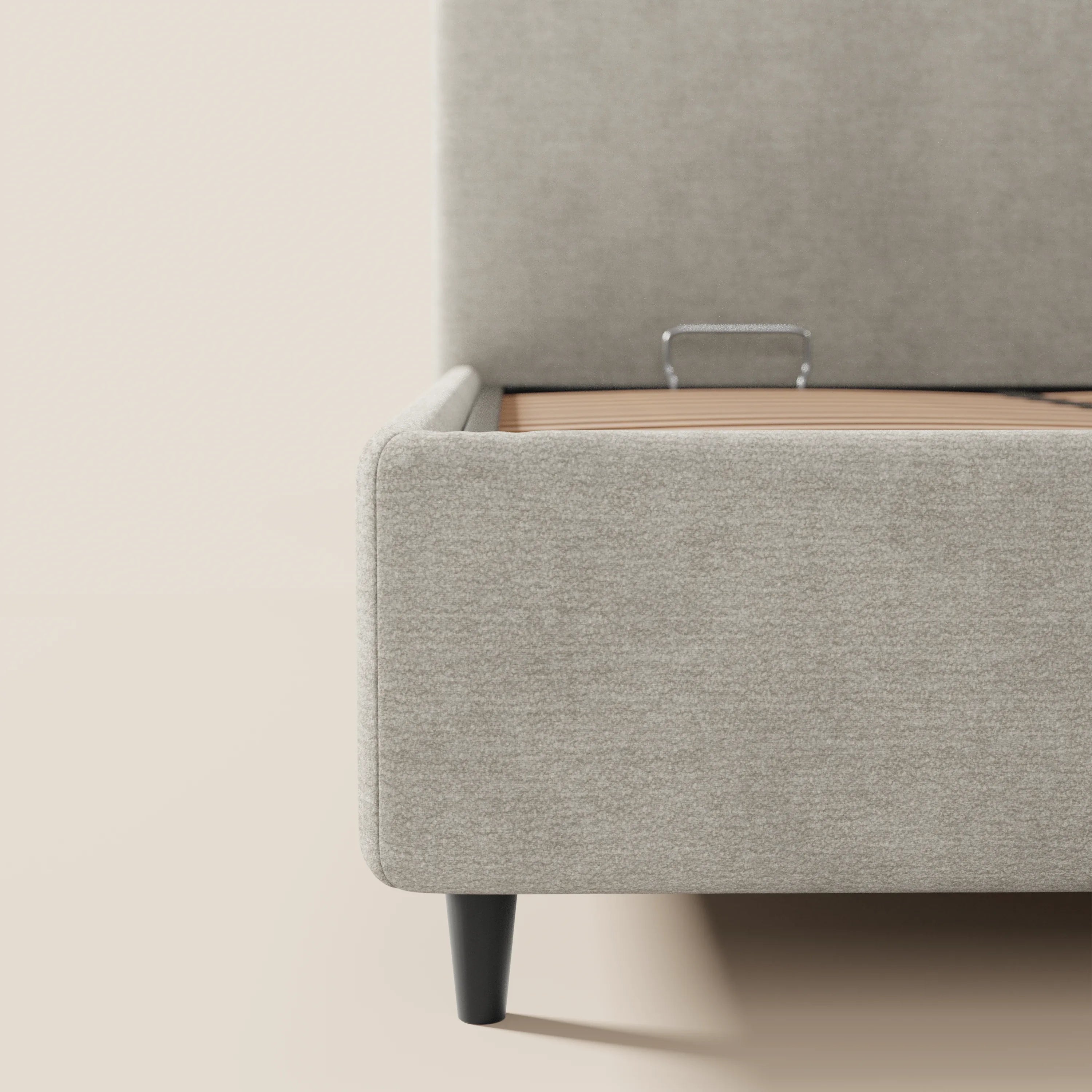 Primo piano del letto imbottito KAELOS in stile minimal di Letti.store: ciniglia beige chiaro con gambe alte in legno nero, testiera, fianchi e pediera arrotondati, oltre a vano contenitore interno, doghe in legno e barra di sostegno del materasso in metallo.