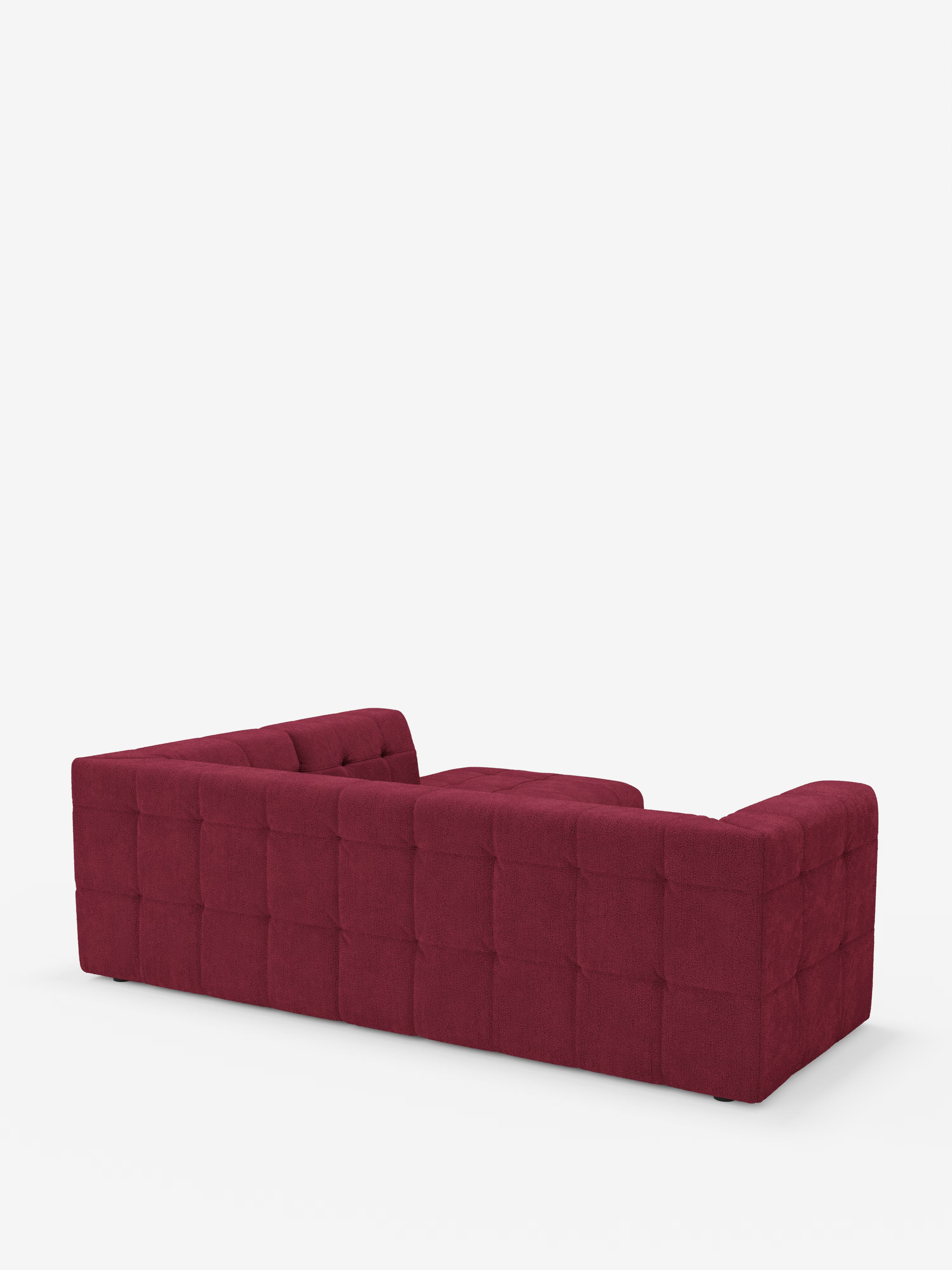 Un divano angolare componibile e modulare Mosaic in bouclé color bordeaux di Divani.Store, caratterizzato da uno schienale basso e da una trapuntatura capitonné quadrata lungo i lati e lo schienale, è perfetto per un soggiorno moderno. Il divano, realizzato in tessuto T21 resistente alle macchie, è raffigurato su uno sfondo bianco a tinta unita con una vista dall’angolo posteriore sinistro, senza cuscini o decorazioni visibili.