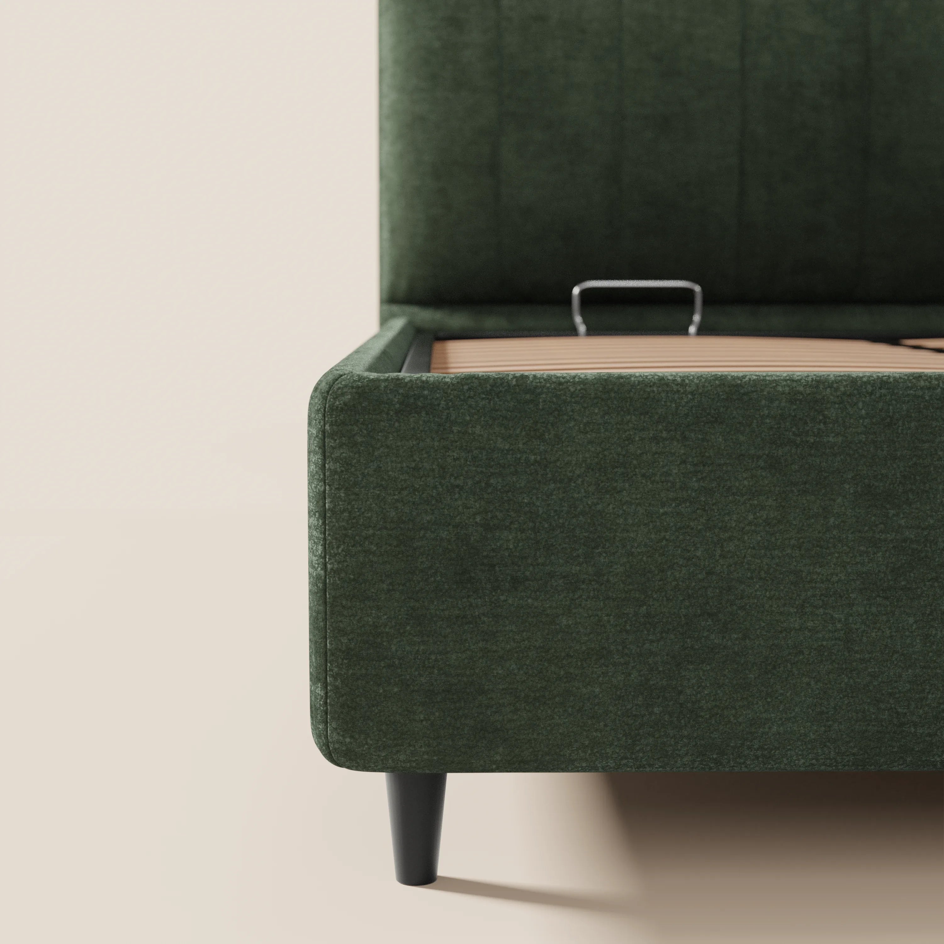 Primo piano del letto imbottito ONYX con vano contenitore e testiera verticale in tessuto Oeko-Tex® di Letti.store, qui raffigurato in verde scuro con gambe nere. Il materasso sollevato rivela un ampio vano contenitore; lo sfondo minimalista ne esalta il design moderno.