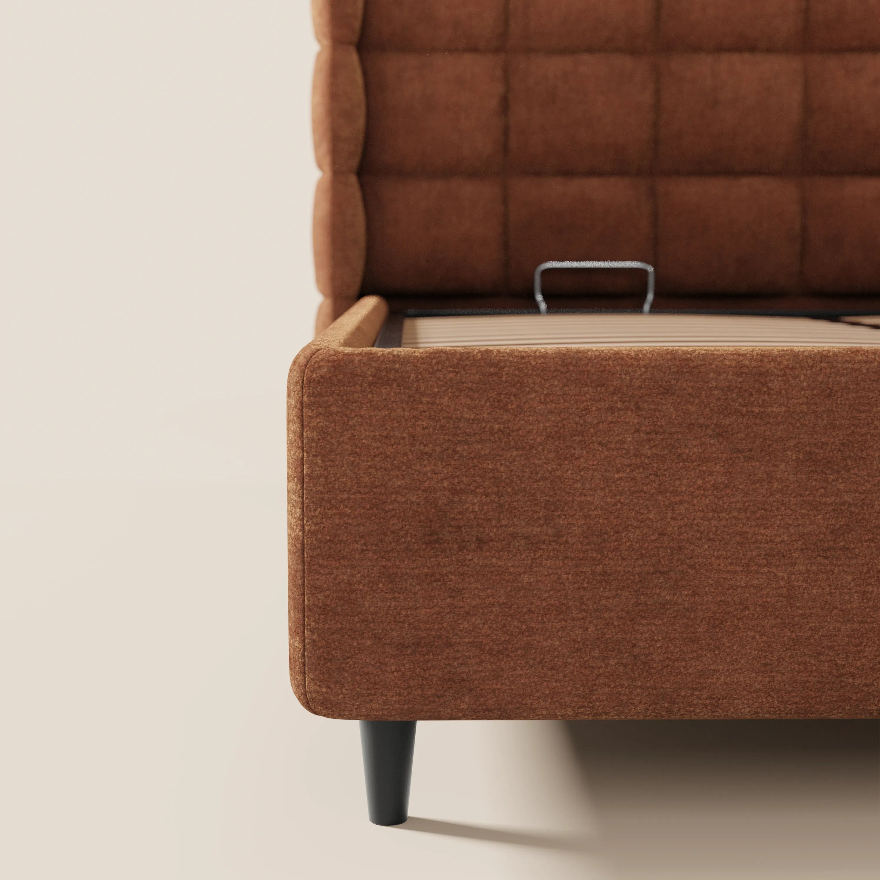 Un primo piano del letto imbottito RAGNAR di Letti.store, con vano contenitore, testiera capitonné avvolgente e rivestimento in tessuto certificato Oeko-Tex®; la base rialzata mostra la barra metallica del meccanismo contenitore.
