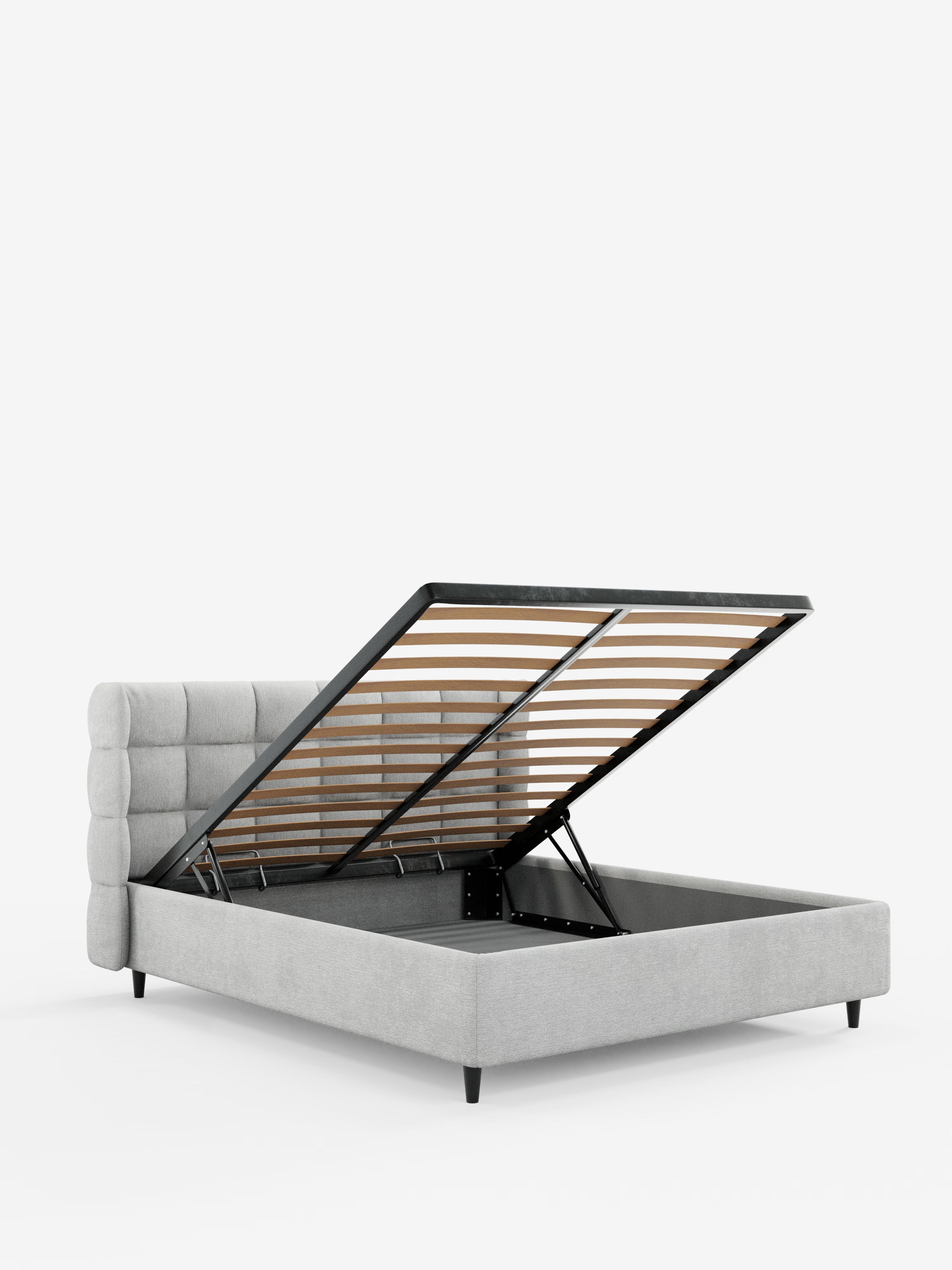 Un letto imbottito RAGNAR in grigio chiaro contemporaneo di Letti.store, caratterizzato da una testiera capitonné imbottita e avvolgente, realizzata in un elegante tessuto certificato Oeko-Tex®. La base del materasso si solleva tramite una cerniera per rivelare un ampio vano contenitore con robuste doghe in legno e supporti in metallo nero. Presentato su uno sfondo bianco a tinta unita.