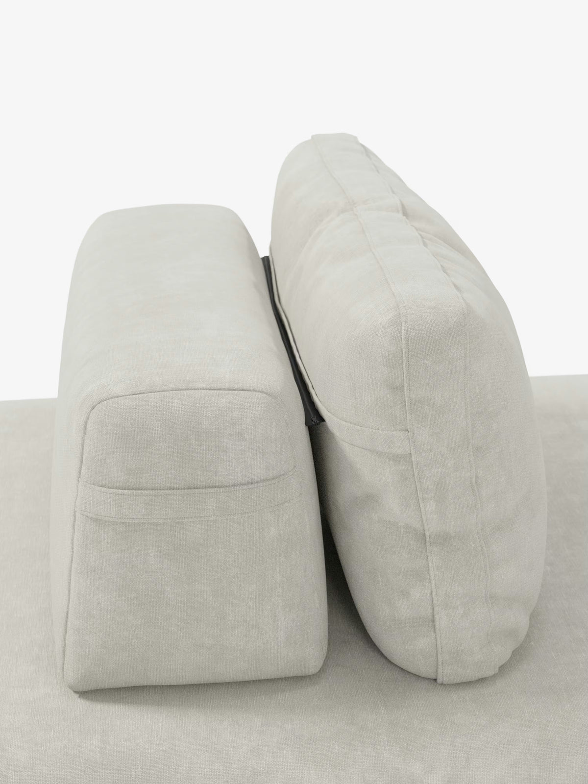 Vista laterale di due cuscini beige chiaro appoggiati su una base coordinata del divano letto matrimoniale Rift da 2 e 3 posti con schienali orientabili, materasso in memory foam alto 24 cm e tessuto T31 antimacchia di Divani.Store. Il cuscino di sinistra appare rettangolare e rigido, mentre quello di destra è più spesso e morbido, a sottolineare il design classico del divano. Una cinghia nera tiene uniti entrambi i cuscini su uno sfondo bianco a tinta unita.