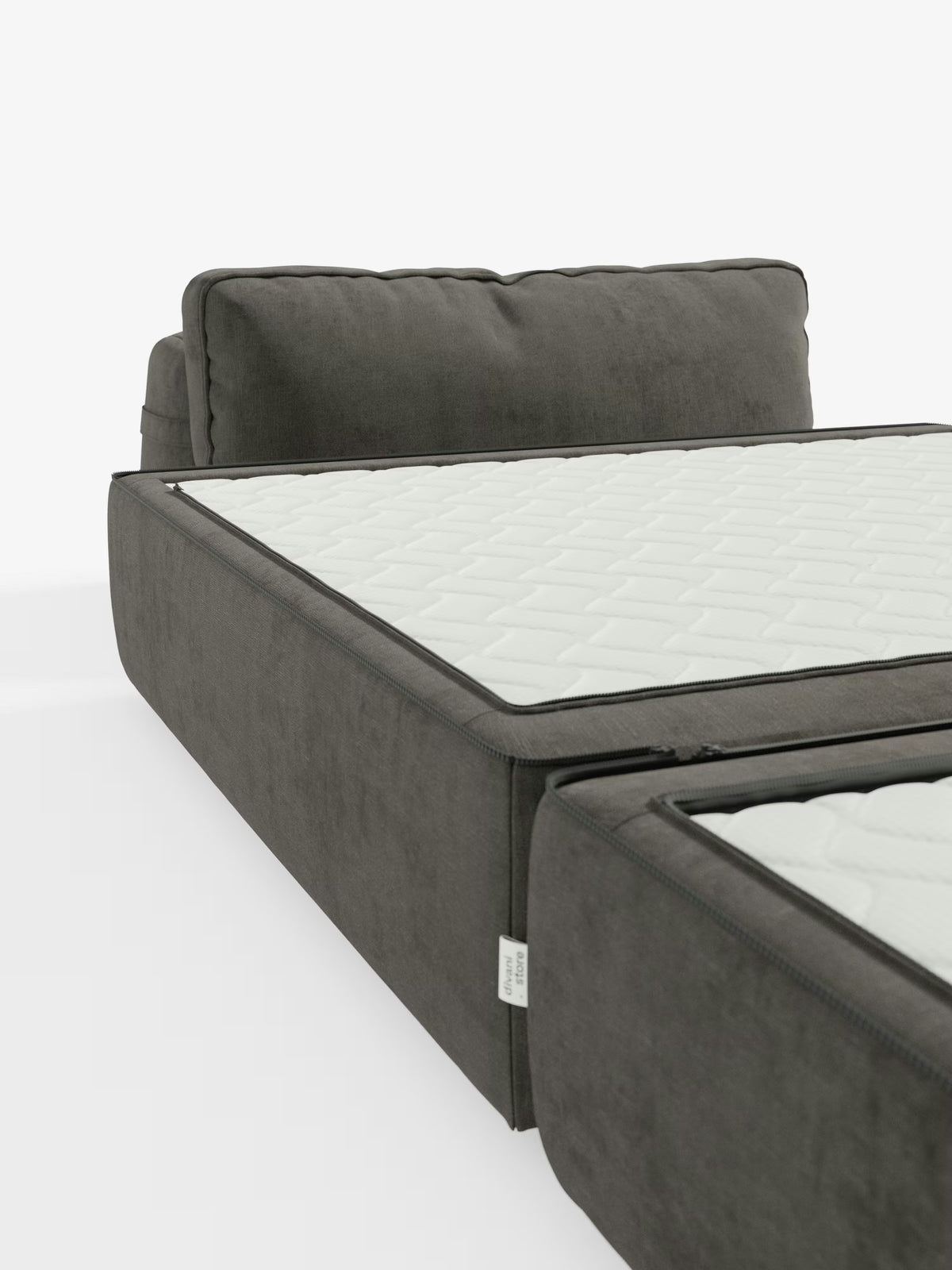 Viene mostrata una poltrona letto Rift di colore grigio scuro di Divani.Store, con il suo materasso in memory foam bianco alto 24 cm, parzialmente aperto per evidenziare il netto passaggio da divano a letto. Lo schienale mobile e il morbido tessuto T31 antimacchia risaltano su uno sfondo bianco a tinta unita, con una piccola etichetta in tessuto fissata sul lato.