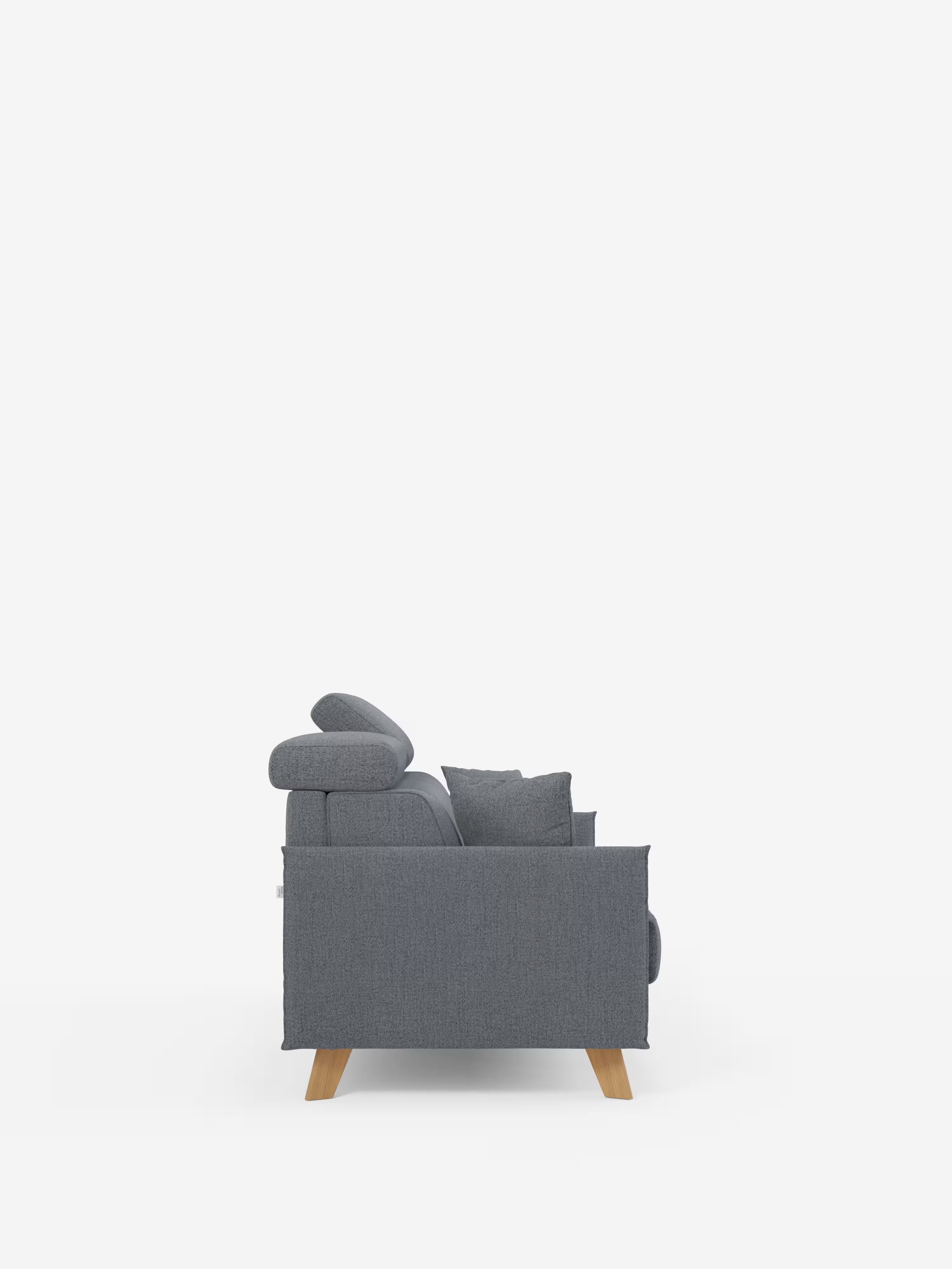 Una vista laterale del divano letto matrimoniale Sole di Divani.Store, caratterizzato da un design compatto e minimalista in grigio moderno, con morbidi cuscini per lo schienale e la seduta, un cuscino, gambe angolate in legno e poggiatesta regolabili. Il rivestimento in tessuto T23, resistente alle macchie e sfoderabile al 100%, risalta sullo sfondo bianco a tinta unita, sottolineandone lo stile scandinavo contemporaneo.