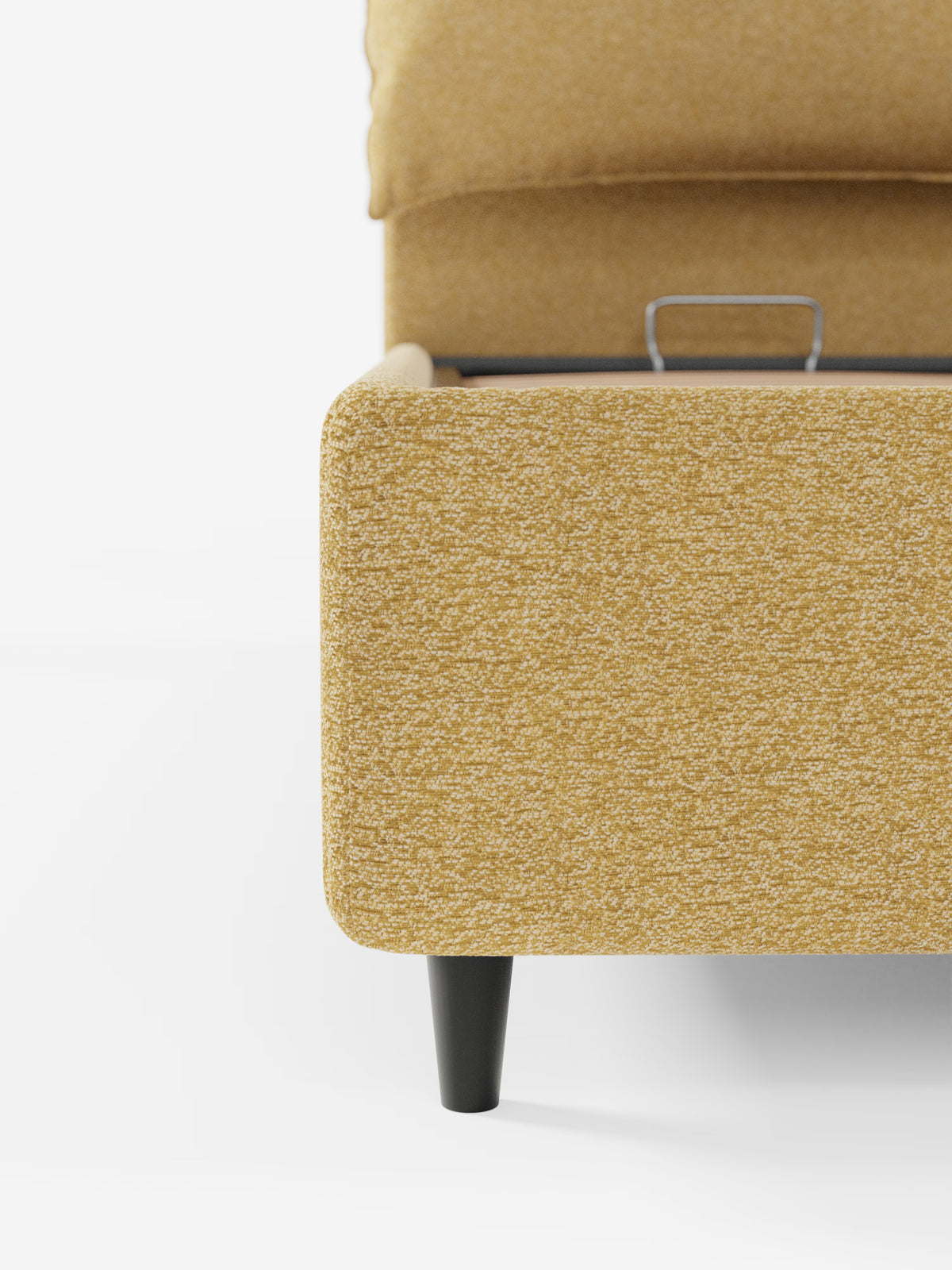Primo piano dell'angolo del letto imbottito ZAYRON di Letti.store, rivestito in tessuto giallo brillante certificato Oeko-Tex®. Una gamba nera sostiene la base, mentre sullo sfondo è visibile parte della maniglia in metallo del vano contenitore integrato. L'immagine è inquadrata su uno sfondo bianco a tinta unita.