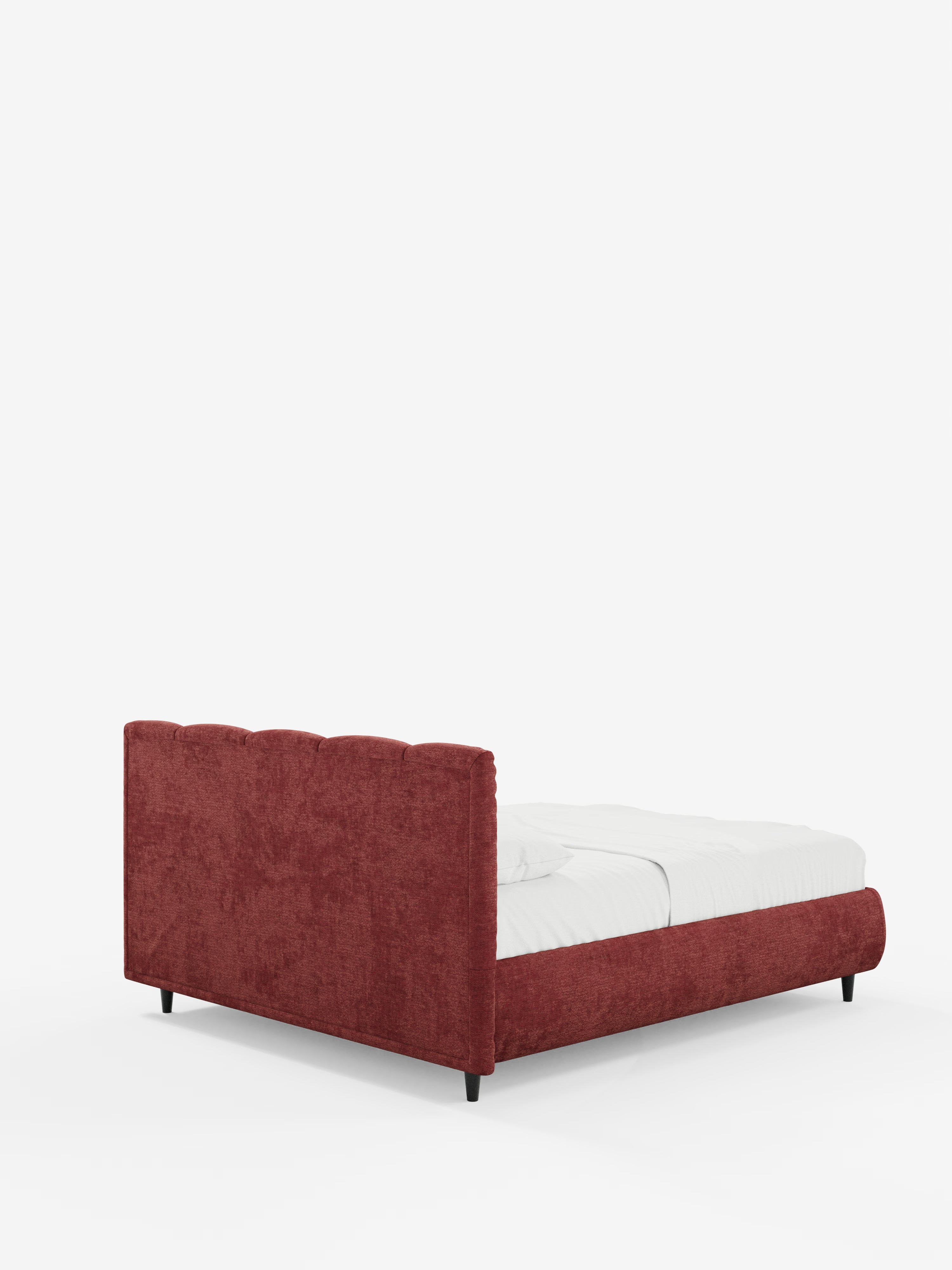 Un letto imbottito ARKAM rosso con contenitore di Letti.store, caratterizzato da una testiera alta con cuciture verticali (testiera a lavorazione verticale) e da una pediera bassa. Il letto è rivestito con biancheria da letto bianca ed è ripreso in una ripresa angolare dal lato posteriore sinistro su uno sfondo bianco a tinta unita. La struttura in tessuto shabby chic, certificata Oeko-Tex®, poggia su gambe corte e scure.