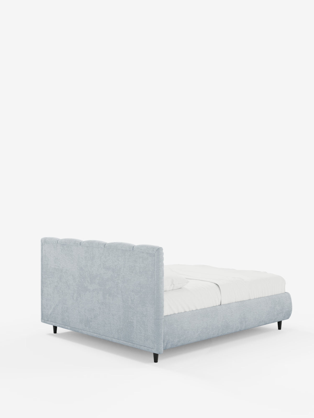 Una vista posteriore obliqua mette in risalto il letto imbottito ARKAM con contenitore e testiera a lavorazione verticale di Letti.store, rivestito in tessuto grigio chiaro certificato Oeko-Tex® in stile shabby chic. La testiera alta, con cuciture verticali, e la pediera bassa conferiscono un aspetto moderno all’arredamento, con la biancheria da letto bianca disposta con cura sul letto, che poggia su corte gambe nere su uno sfondo bianco a tinta unita.
