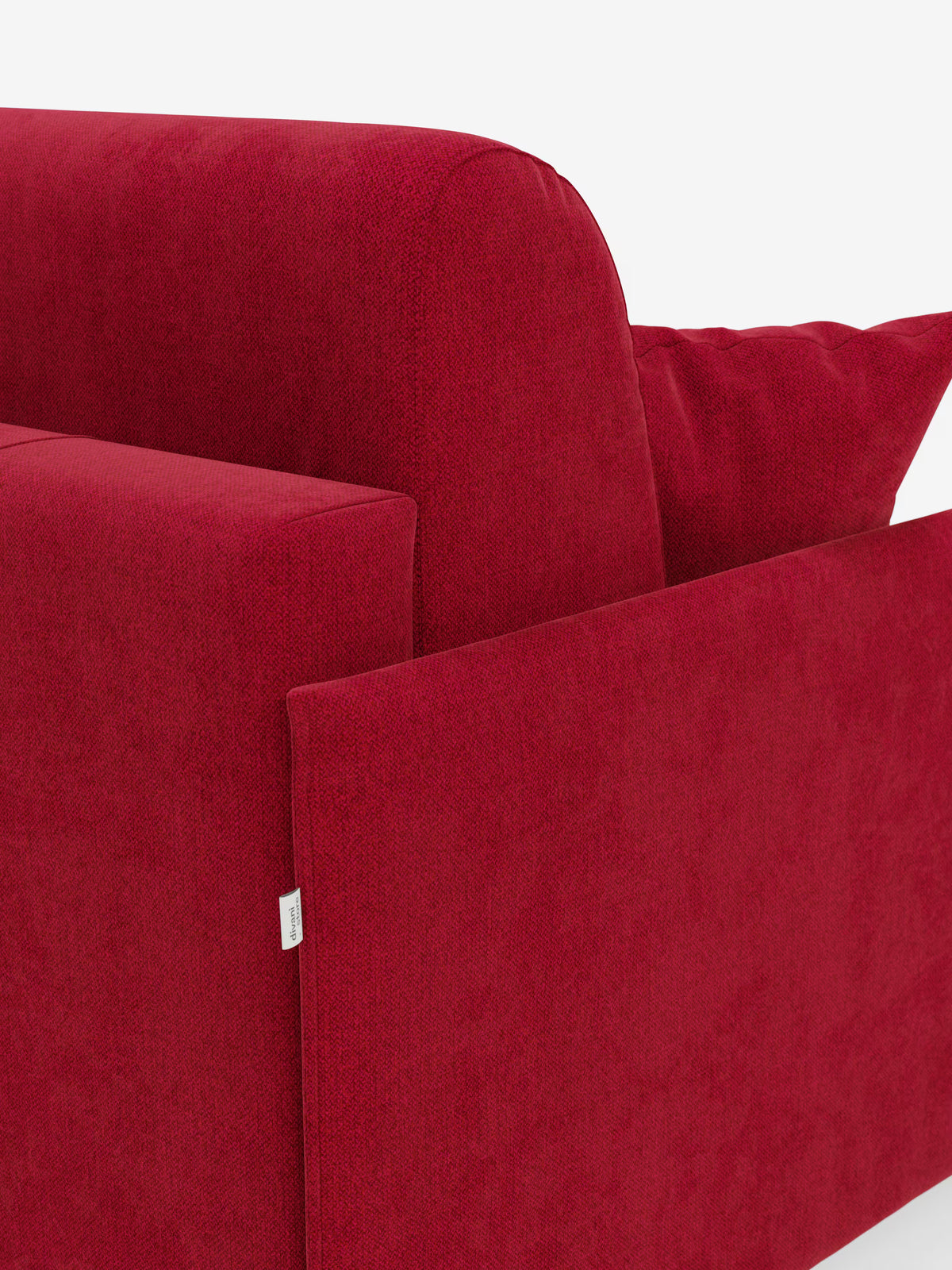 Primo piano del moderno divano letto matrimoniale rosso Evans sfoderabile di Divani.Store, ripreso su sfondo bianco. L'immagine mette in risalto il bracciolo sinistro, la seduta, lo schienale e un cuscino coordinato in tessuto smacchiabile T23. Una piccola etichetta bianca con una scritta è applicata vicino al bordo inferiore del bracciolo. Questo design compatto presenta linee pulite e spigolose e include un pratico vano porta guanciali.