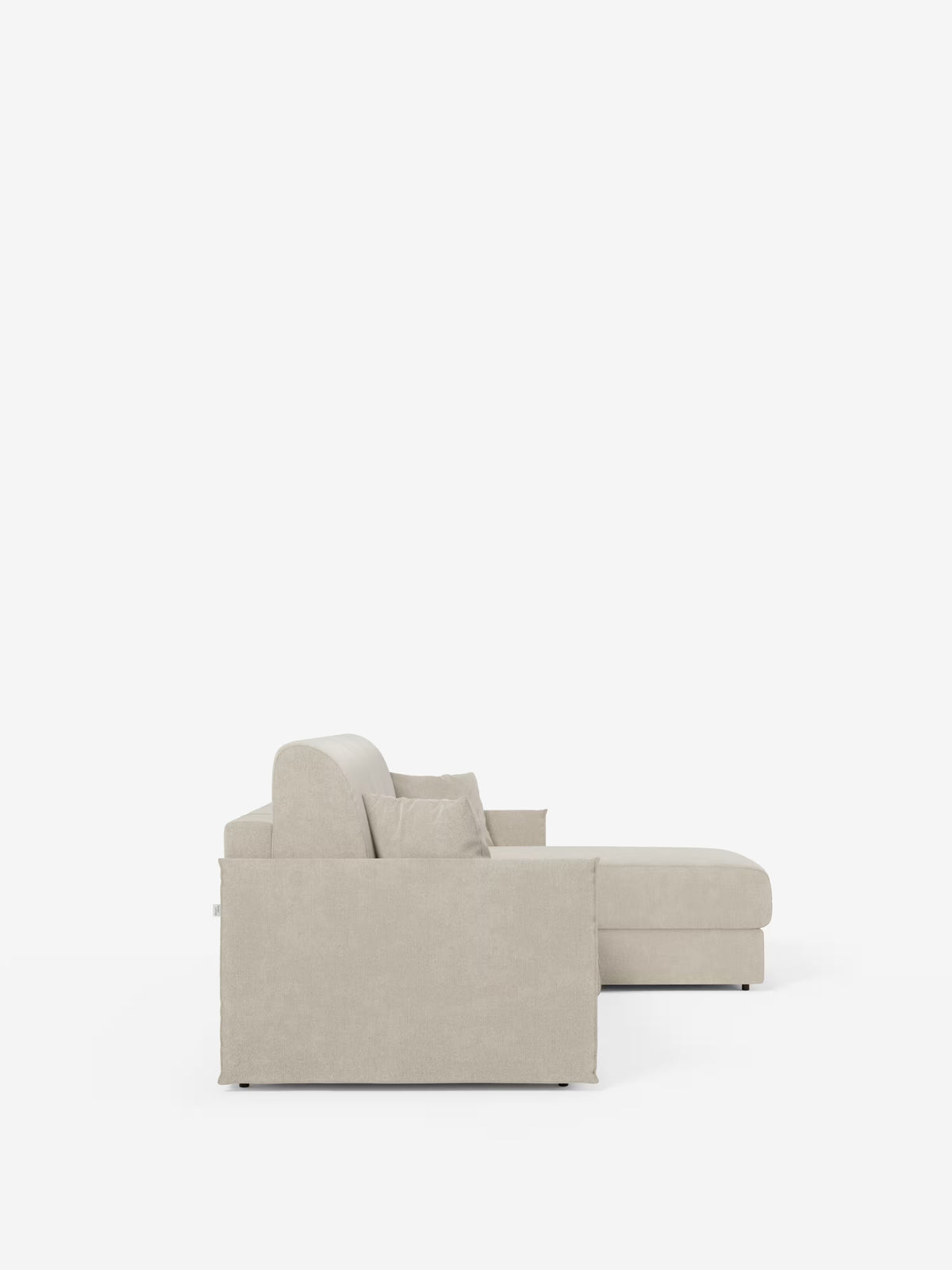 Vista laterale del divano letto angolare con penisola contenitore Evans di Divani.Store in beige chiaro, caratterizzato da una chaise longue rivolta a destra con pratico vano contenitore. Questo divano letto compatto si distingue per le linee pulite, i braccioli piatti e due cuscini coordinati su uno sfondo bianco a tinta unita, che ne esaltano il design moderno e minimalista, realizzato in tessuto T23 antimacchia.