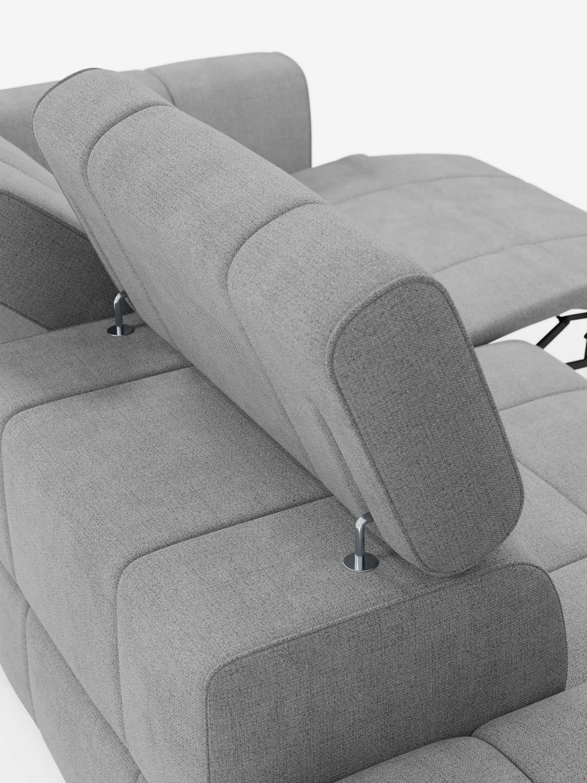 Un divano componibile Giotto di colore grigio chiaro con estremità aperta – opzione relax elettrico in tessuto smacchiabile T23 con poggiatesta regolabile, sottili supporti in metallo e poggiapiedi allungato sulla destra, su sfondo bianco.