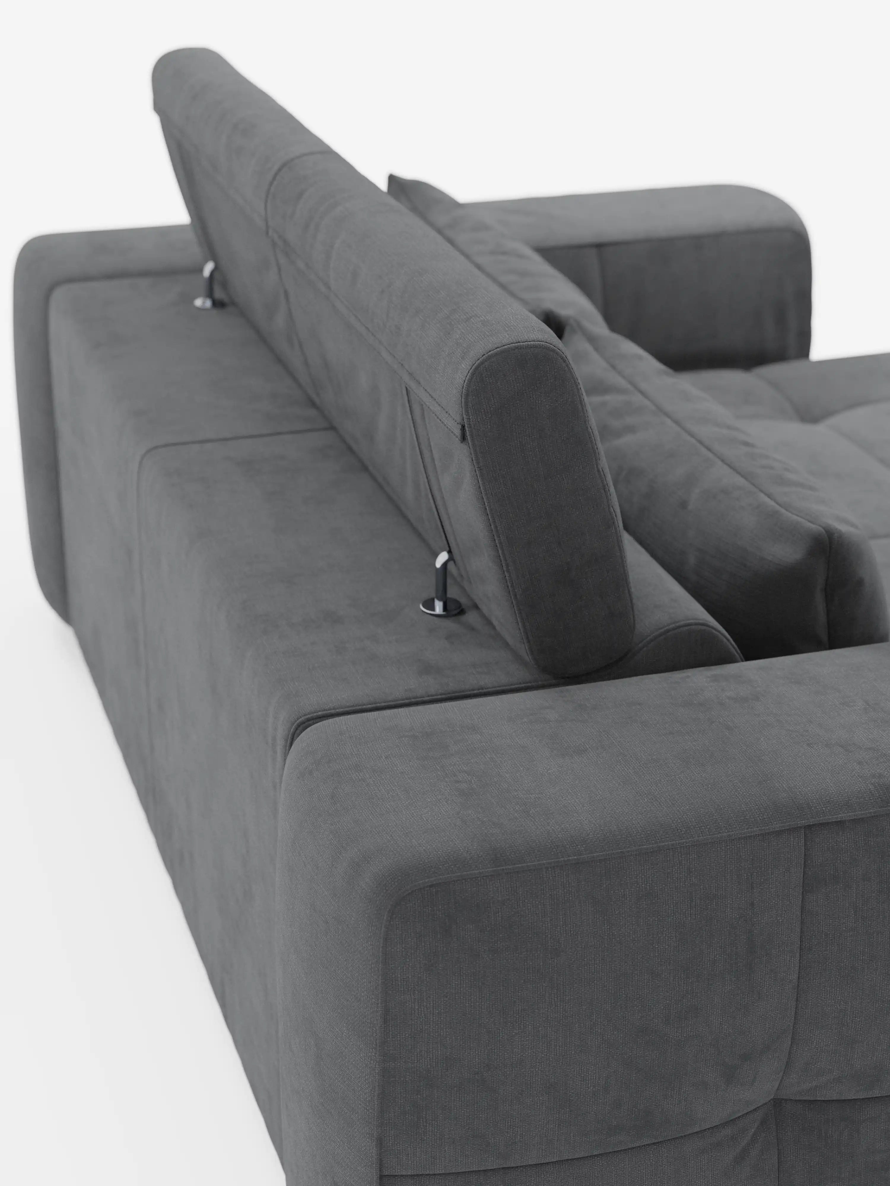 Un divano Monarch grigio scuro con funzione relax elettrica per l’allungamento delle sedute e poggiatesta reclinabile, rivestito in morbido tessuto smacchiabile T31 di Divani.Store, visto di sbieco dall’angolo posteriore. Il rivestimento appare morbido e questo moderno divano componibile presenta un design squadrato con braccioli spessi e supporti in metallo per i poggiatesta regolabili.