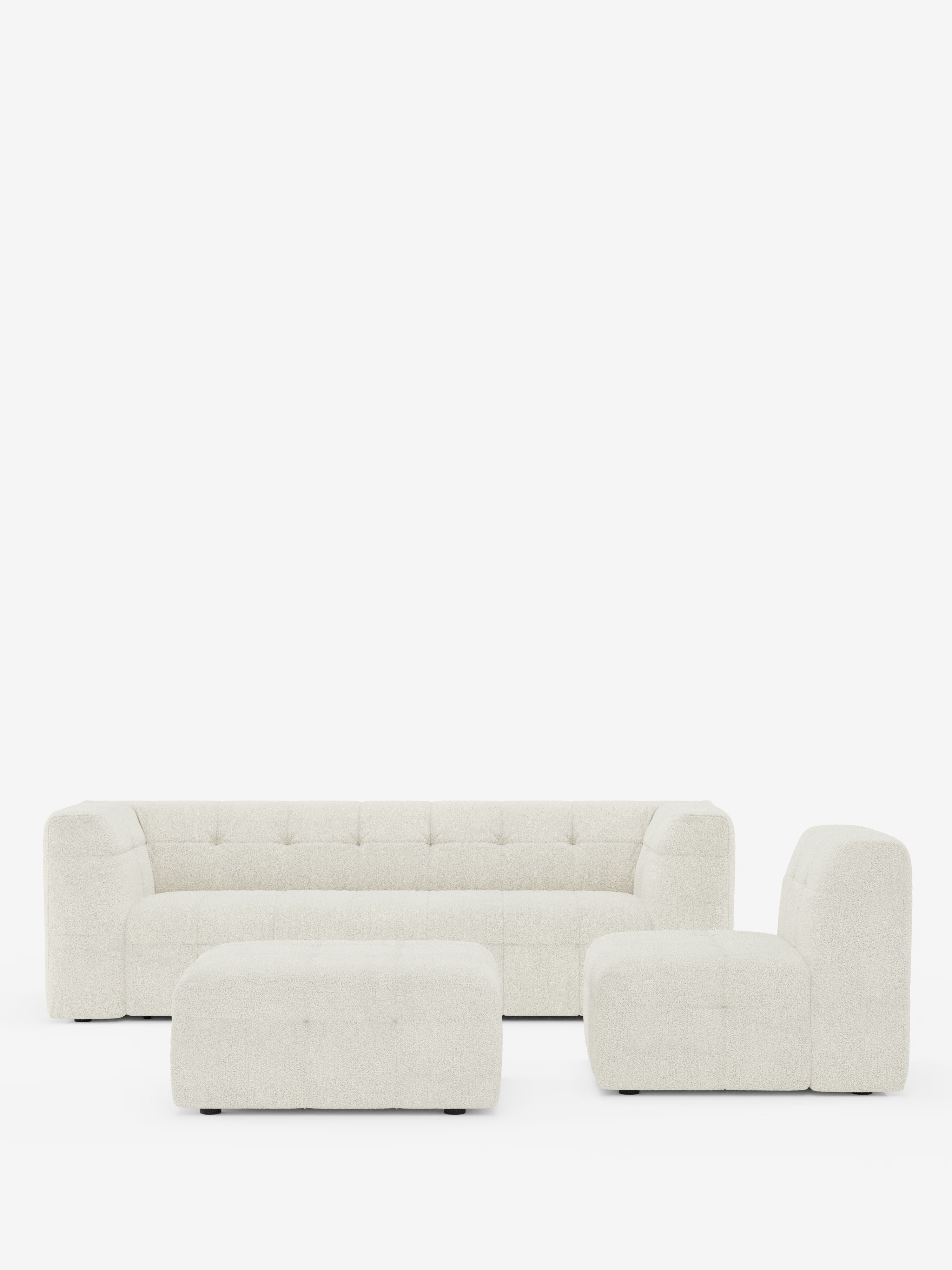 Una moderna e minimalista composizione per soggiorno firmata Divani.Store mette in risalto il divano angolare componibile e modulare Mosaic in bouclé: capitonné e design in tessuto smacchiabile T21 — un lungo divano componibile color crema con bordi arrotondati e texture morbida — abbinato a una poltrona coordinata senza braccioli e a un pouf rettangolare. Ogni elemento è caratterizzato da un morbido rivestimento in bouclé, profili bassi e si staglia su uno sfondo bianco a tinta unita.