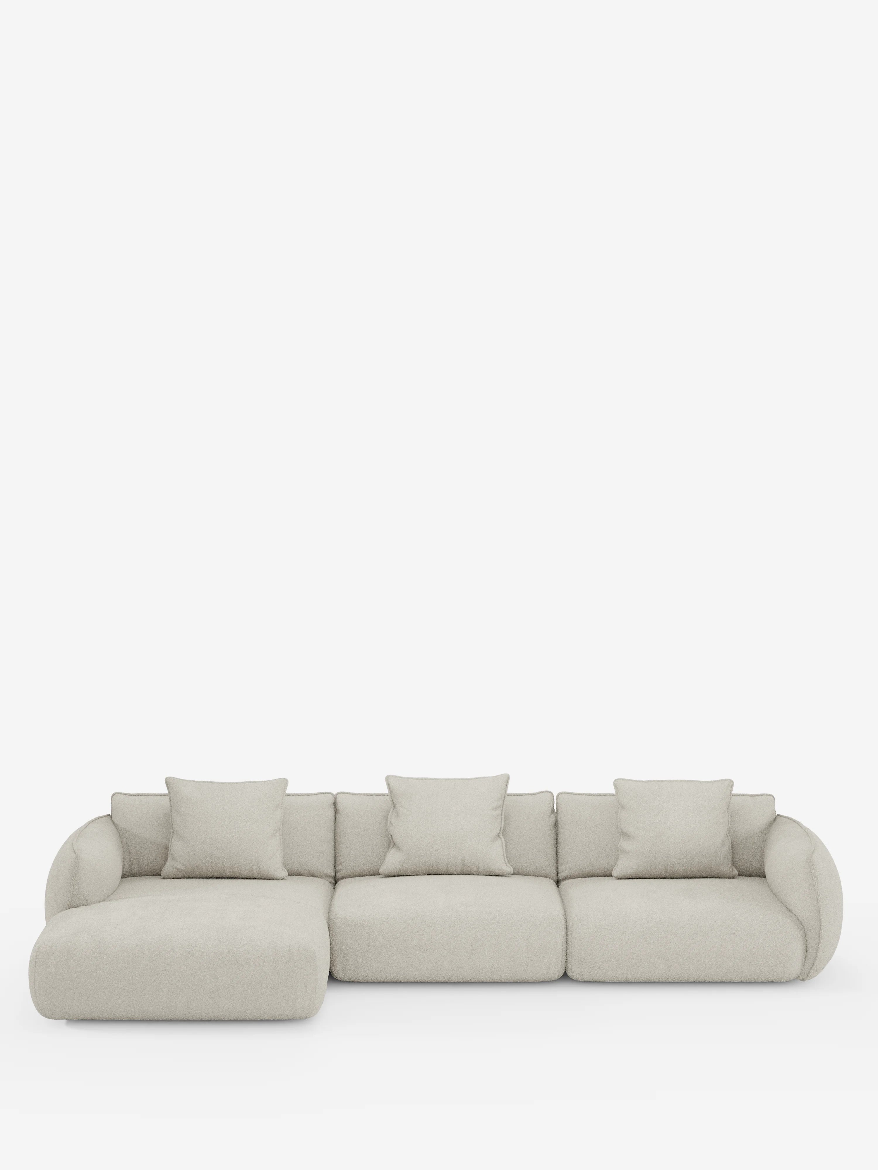 Il divano angolare con penisola componibile Nimbus di Divani.Store è un divano componibile moderno, di colore beige chiaro, con tre posti e una chaise longue sul lato sinistro. Rivestito in morbido tessuto effetto cotone antimacchia (T33), presenta braccioli arrotondati ed è corredato da quattro cuscini quadrati coordinati, che risaltano magnificamente sullo sfondo bianco a tinta unita.