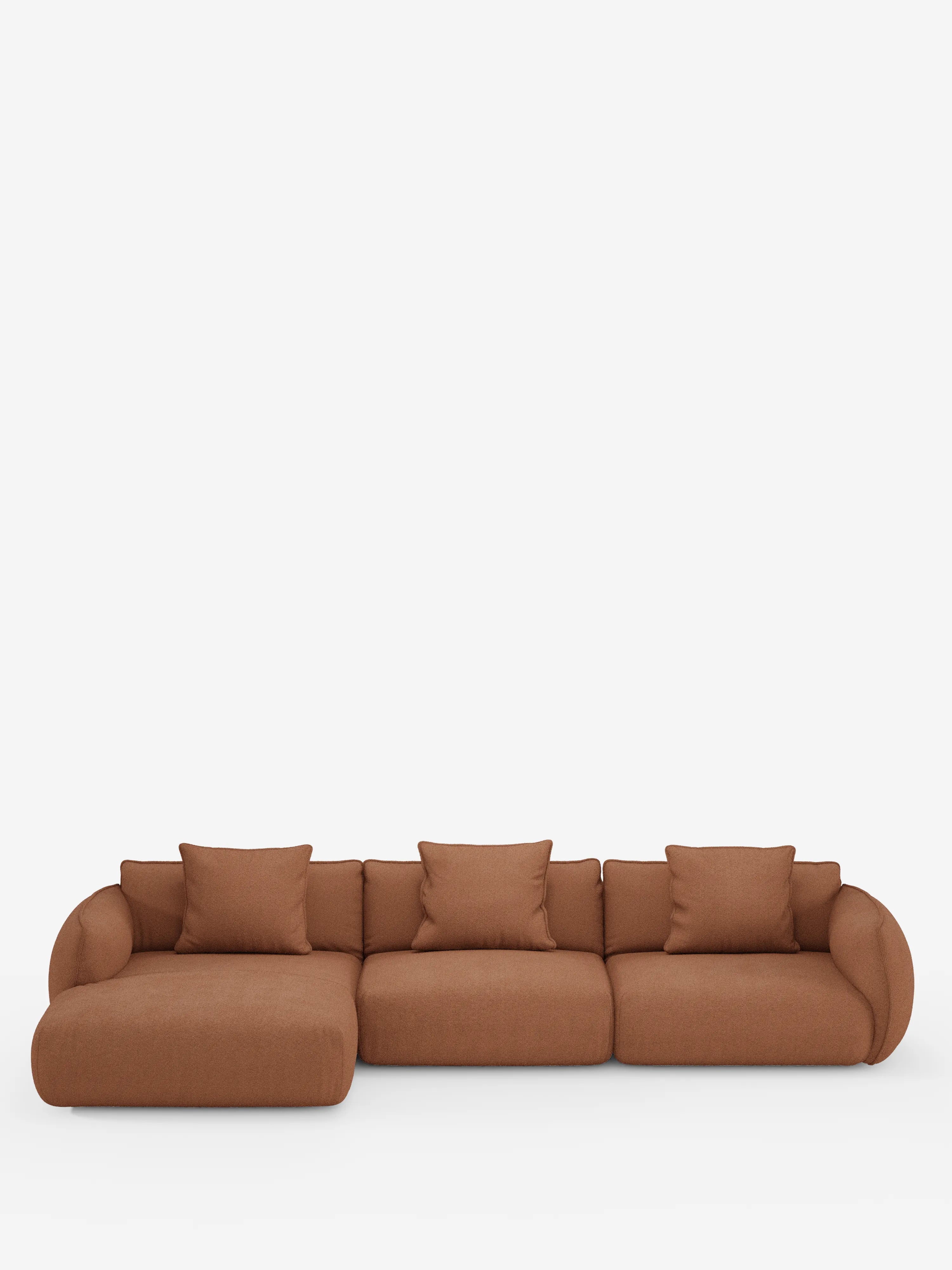 Un moderno divano angolare a tre elementi Nimbus con penisola componibile di Divani.Store, rivestito in tessuto T33 effetto cotone color ruggine e resistente alle macchie, caratterizzato da braccioli arrotondati e cinque cuscini quadrati abbinati, che risaltano su uno sfondo bianco a tinta unita.