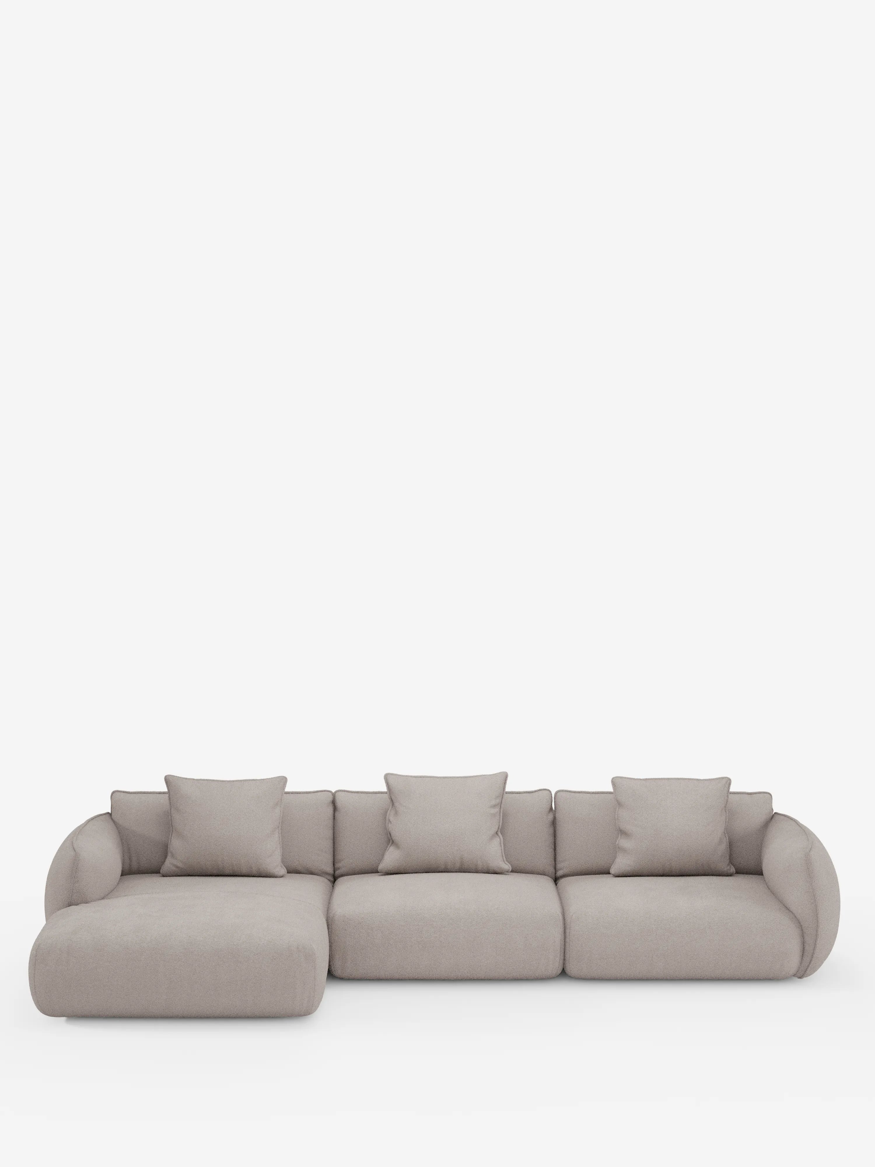 Il divano angolare con penisola componibile Nimbus in morbido tessuto effetto cotone smacchiabile T33 di Divani.Store è un divano componibile moderno, di colore beige chiaro, composto da tre posti principali e una chaise longue orientata a sinistra. Questo divano contemporaneo include quattro cuscini schienale coordinati e presenta braccioli arrotondati dal design minimalista e imbottito. Lo sfondo è bianco a tinta unita.
