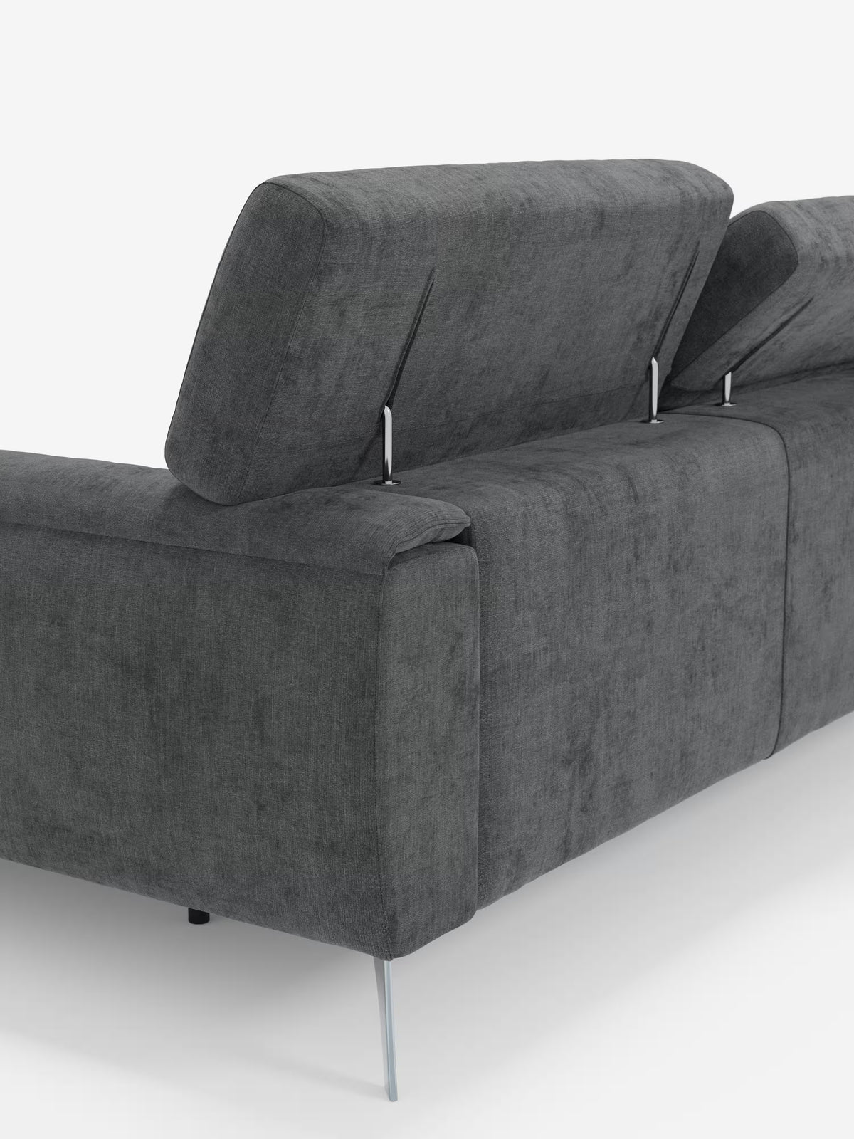 Un primo piano del divano angolare con penisola e sedute scorrevoli Caravaggio in tessuto smacchiabile T31 di Divani.Store, caratterizzato da un moderno rivestimento in tessuto grigio scuro, poggiatesta regolabili, sedute scorrevoli e sottili gambe in metallo. L'immagine mette in risalto la parte posteriore e laterale del divano, evidenziandone la superficie strutturata e il design elegante e minimalista su uno sfondo bianco a tinta unita.