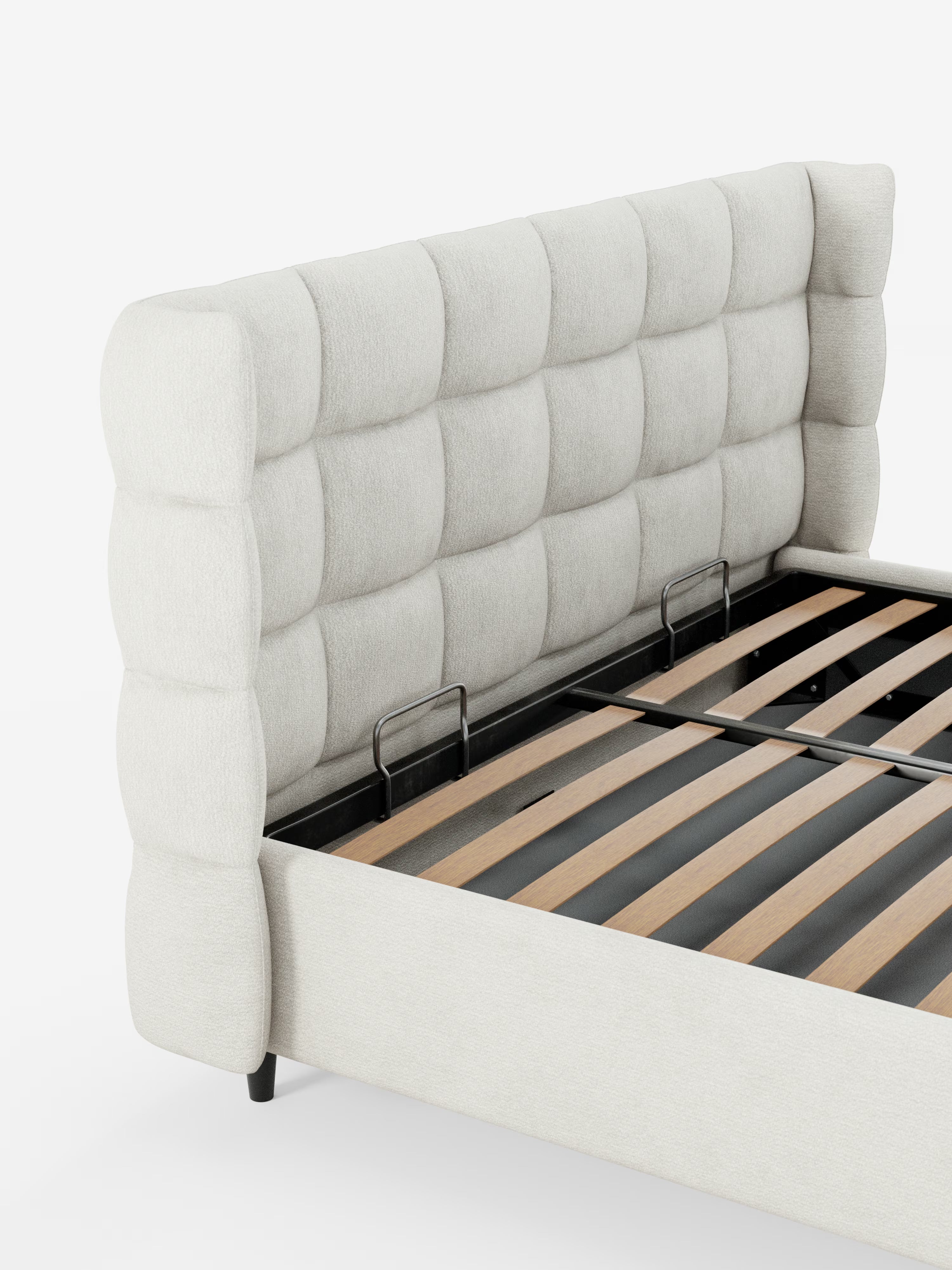Un primo piano del letto imbottito RAGNAR con contenitore e testiera capitonné avvolgente di Letti.store, caratterizzato da un'alta testiera imbottita color beige chiaro, realizzata in elegante tessuto certificato Oeko-Tex® con raffinato effetto capitonné. Sono visibili le robuste doghe in legno e i supporti per il materasso in metallo nero, mentre il letto poggia su corte gambe nere su uno sfondo bianco a tinta unita: ideale per conferire uno stile contemporaneo a qualsiasi camera da letto.