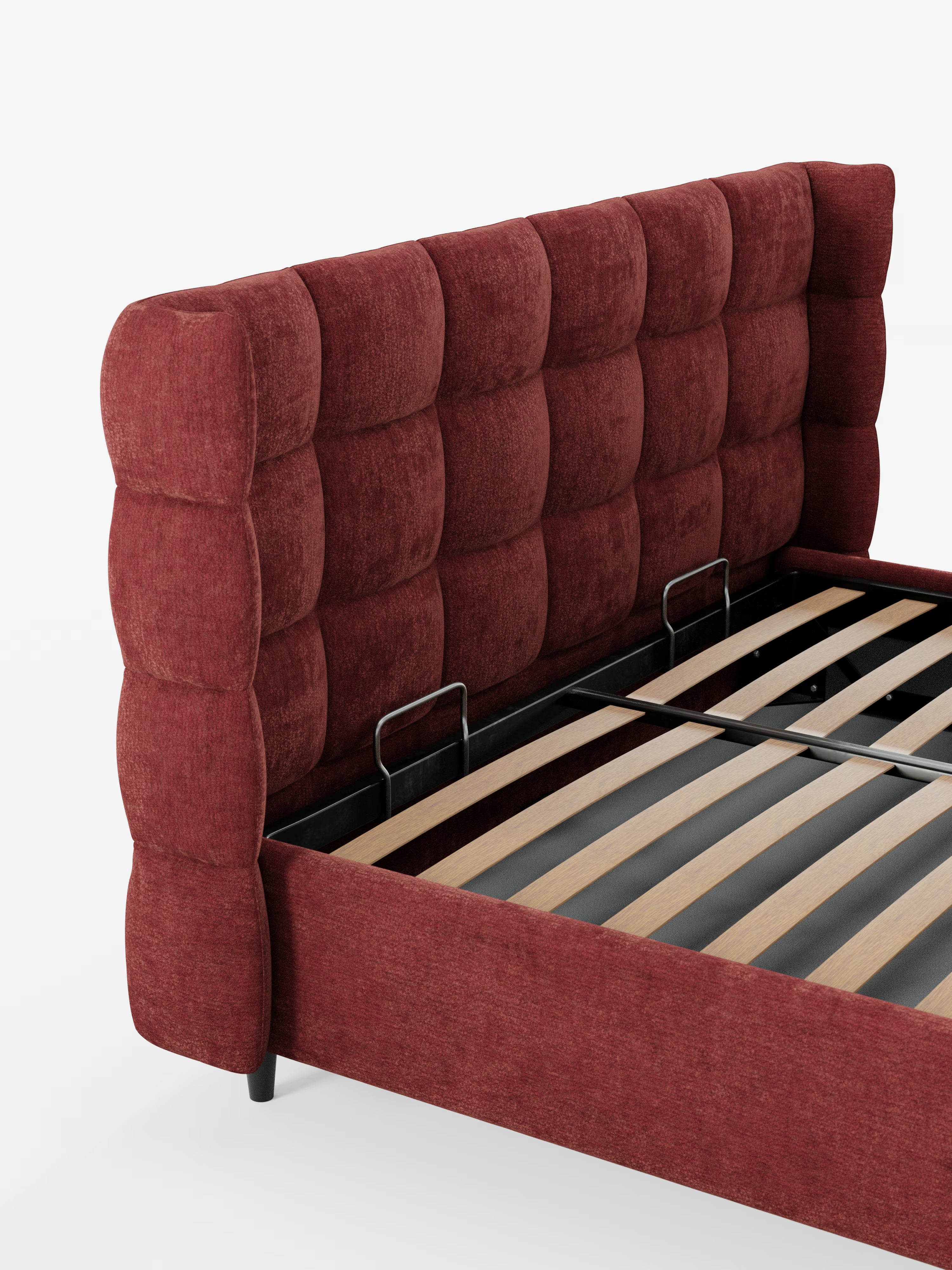 Un primo piano del letto imbottito RAGNAR con contenitore e testiera capitonné avvolgente di Letti.store, caratterizzato da un'alta testiera avvolgente in velluto bordeaux trapuntato e da un pannello laterale coordinato in elegante tessuto certificato Oeko-Tex®. La struttura è dotata di doghe in legno e robusti supporti in metallo nero; nella foto è raffigurata senza materasso su uno sfondo bianco a tinta unita.