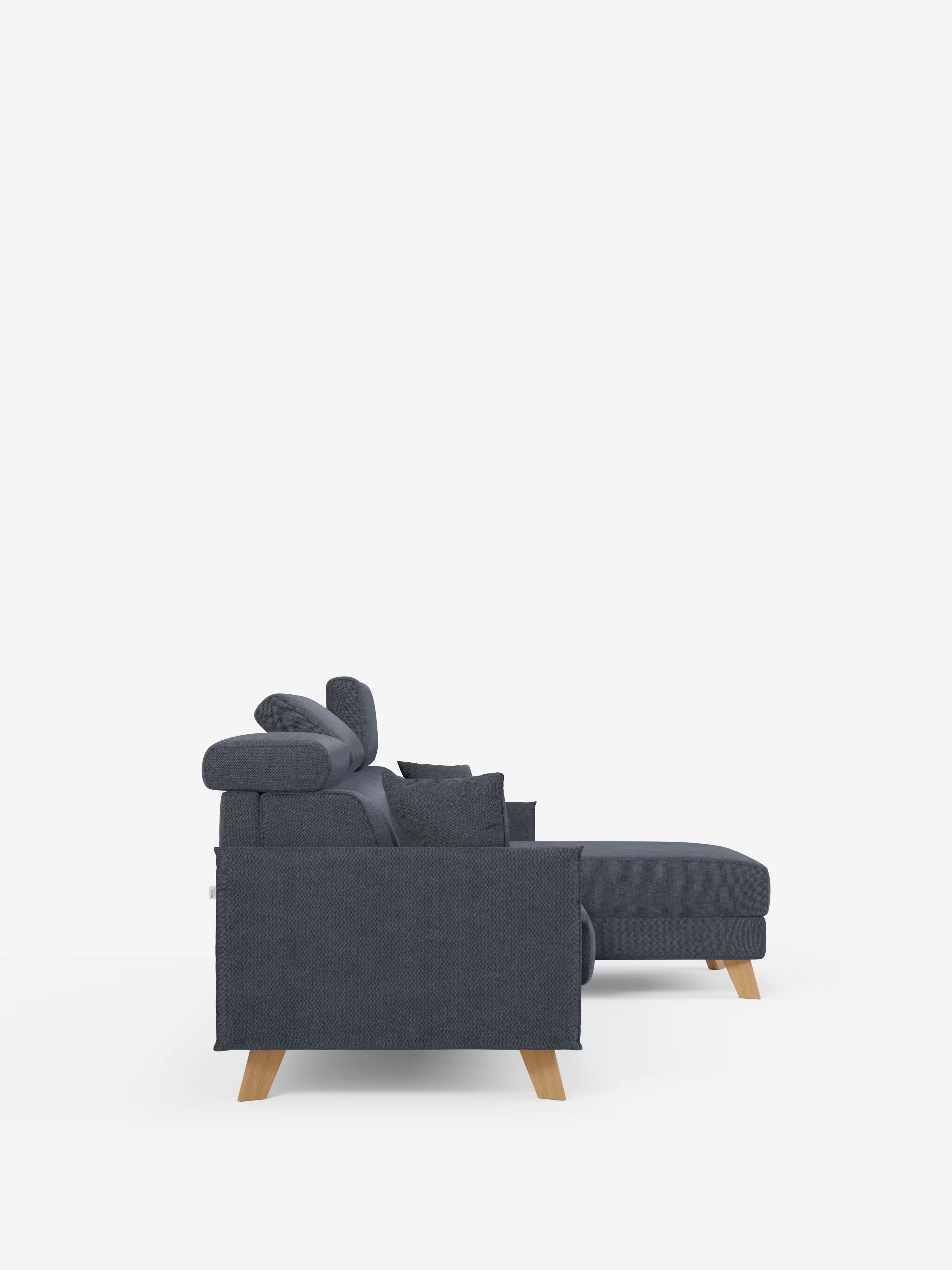 Vista laterale del divano letto matrimoniale angolare “Sole” con penisola contenitore e poggiatesta reclinabili di Divani.Store, rivestito in tessuto T23 grigio scuro smacchiabile. Questo moderno divano letto è dotato di chaise longue, gambe angolari in legno, poggiatesta regolabili e cuscini coordinati, il tutto presentato su uno sfondo bianco a tinta unita. Il design elegante rivela influenze dello stile scandinavo, creando un connubio tra eleganza contemporanea e confortevole funzionalità.