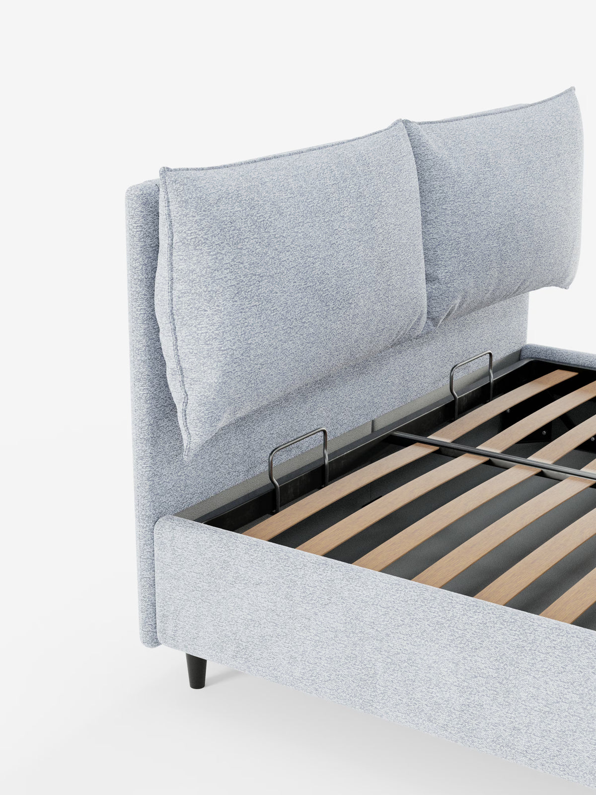 Su uno sfondo bianco è raffigurata una vista parziale del letto imbottito ZAYRON con contenitore e morbidi cuscini regolabili di Letti.store. Questo letto moderno presenta una testiera in tessuto grigio chiaro certificato Oeko-Tex® con due grandi e morbidi cuscini regolabili, completata da doghe in legno a vista e supporti in metallo nero.