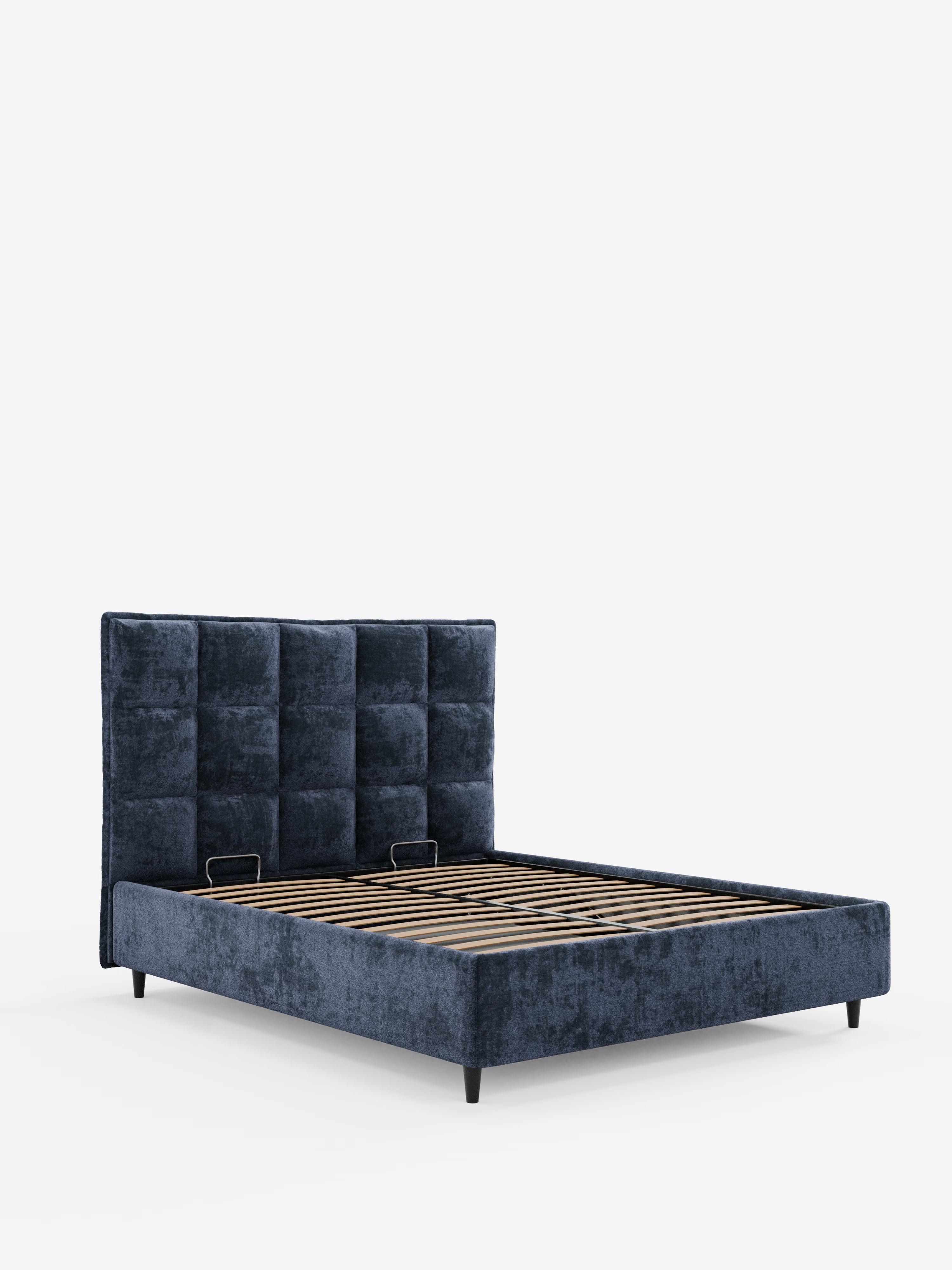 Il letto imbottito AURO con contenitore e testiera capitonné alta in ciniglia Oeko-Tex® di Letti.store presenta un design moderno, rivestito in blu navy, con un'elegante testiera capitonné alta a motivo quadrato. La sua base a piattaforma, dotata di doghe in legno per il sostegno del materasso, poggia su corte gambe nere, creando un look semplice e minimalista che risalta sullo sfondo bianco.