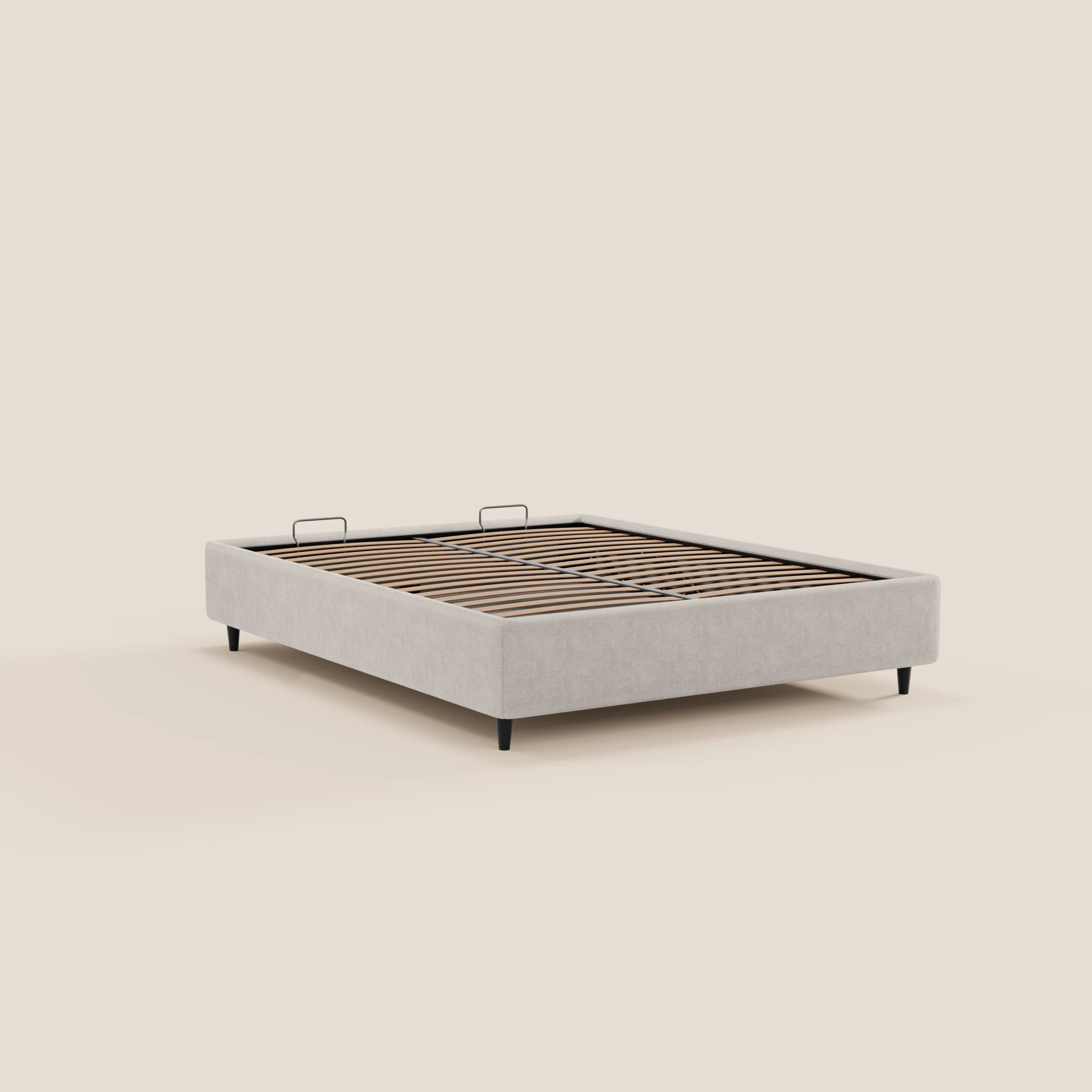 Il letto sommier imbottito ERON di Letti.store presenta una base in tessuto impermeabile color beige chiaro, certificato Oeko-Tex, doghe in legno a vista, quattro gambe nere e due maniglie in metallo che gli conferiscono un look moderno. Lo sfondo semplice mette in risalto il suo design minimalista.