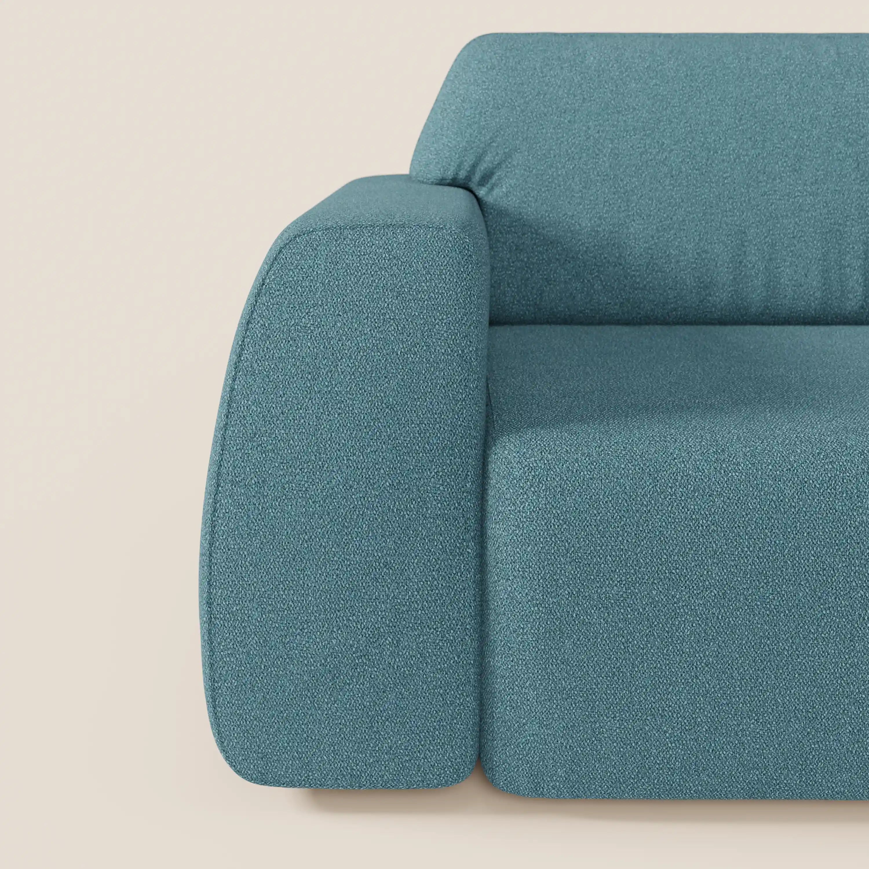 Primo piano del divano Orbit con 3 sedute scorrevoli e allungabili di Divani.Store, in tessuto effetto cotone smacchiabile T33 verde acqua, che mostra il bracciolo sinistro, l'imbottitura in peluche, le curve morbide e lo sfondo minimalista color crema chiaro.