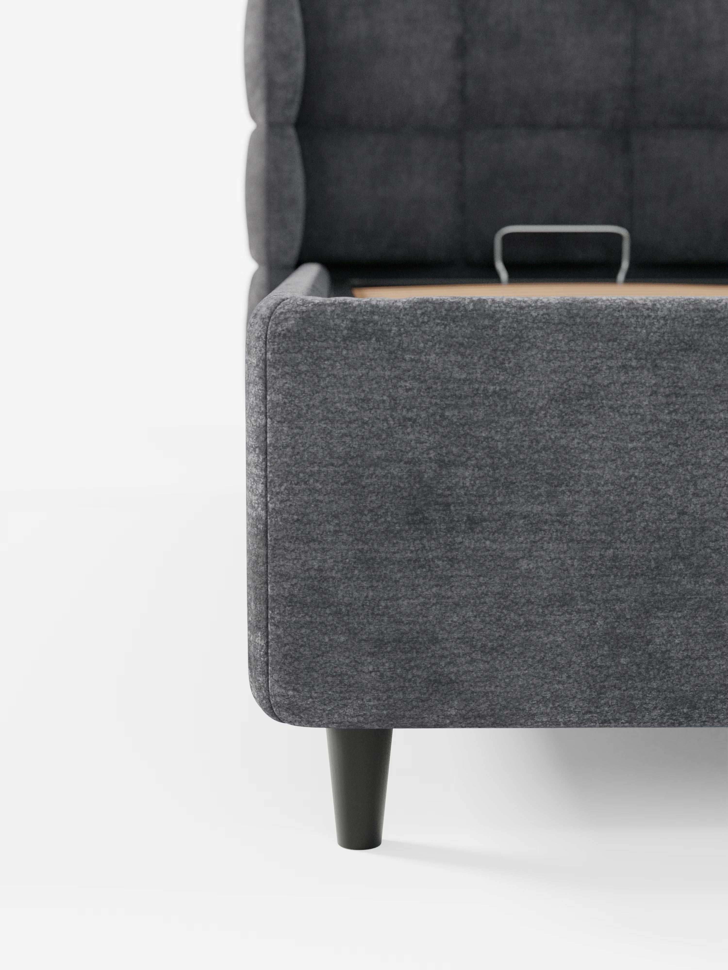 Immagine ravvicinata del letto imbottito RAGNAR con contenitore e testiera capitonné avvolgente di Letti.store, qui presentato in un elegante tessuto grigio scuro certificato Oeko-Tex® con gambe nere, caratterizzato da una testiera capitonné avvolgente e da una discreta maniglia in metallo sul vano contenitore nascosto. Lo sfondo è bianco a tinta unita.