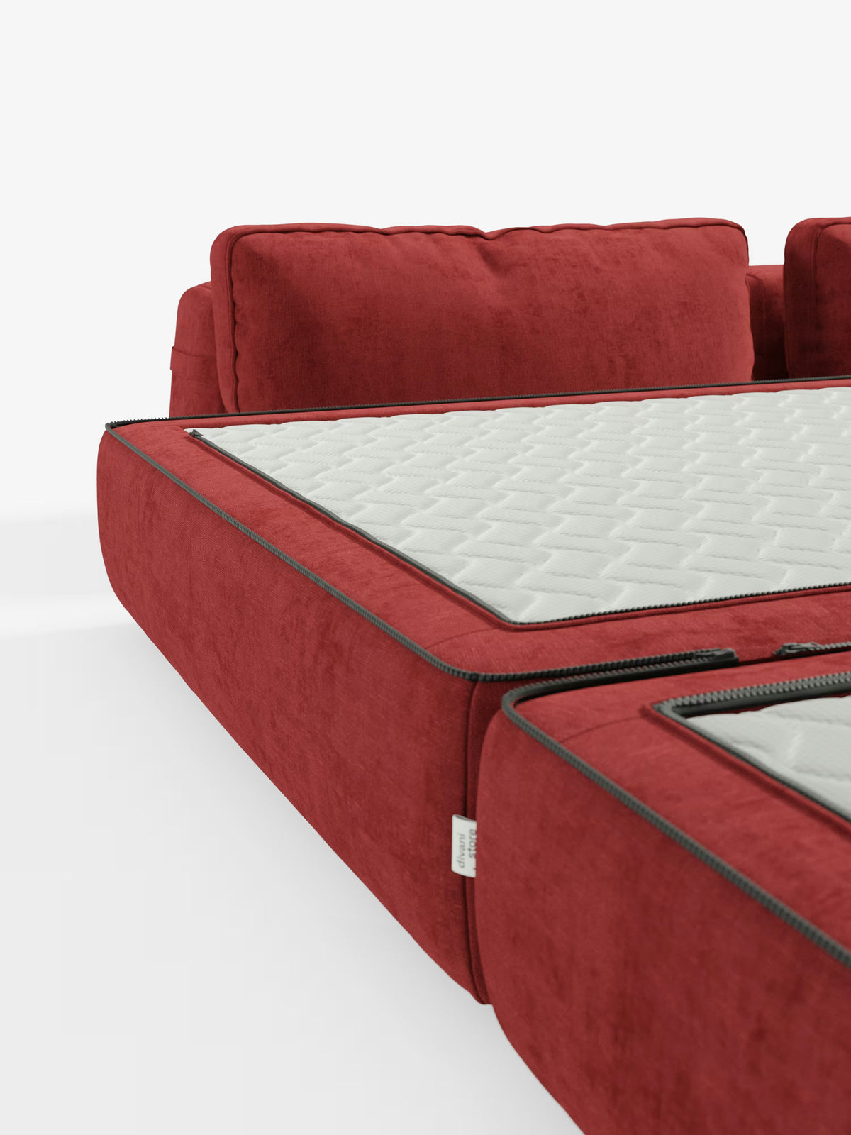 Un primo piano del moderno divano letto matrimoniale Rift di Divani.Store, presentato in rosso con cuscini, caratterizzato da schienali regolabili, una cerniera a vista e un materasso sfoderabile trapuntato bianco (alto 24 cm, con schiuma memory e tessuto T31 antimacchia), esposto in un ambiente luminoso e minimalista.