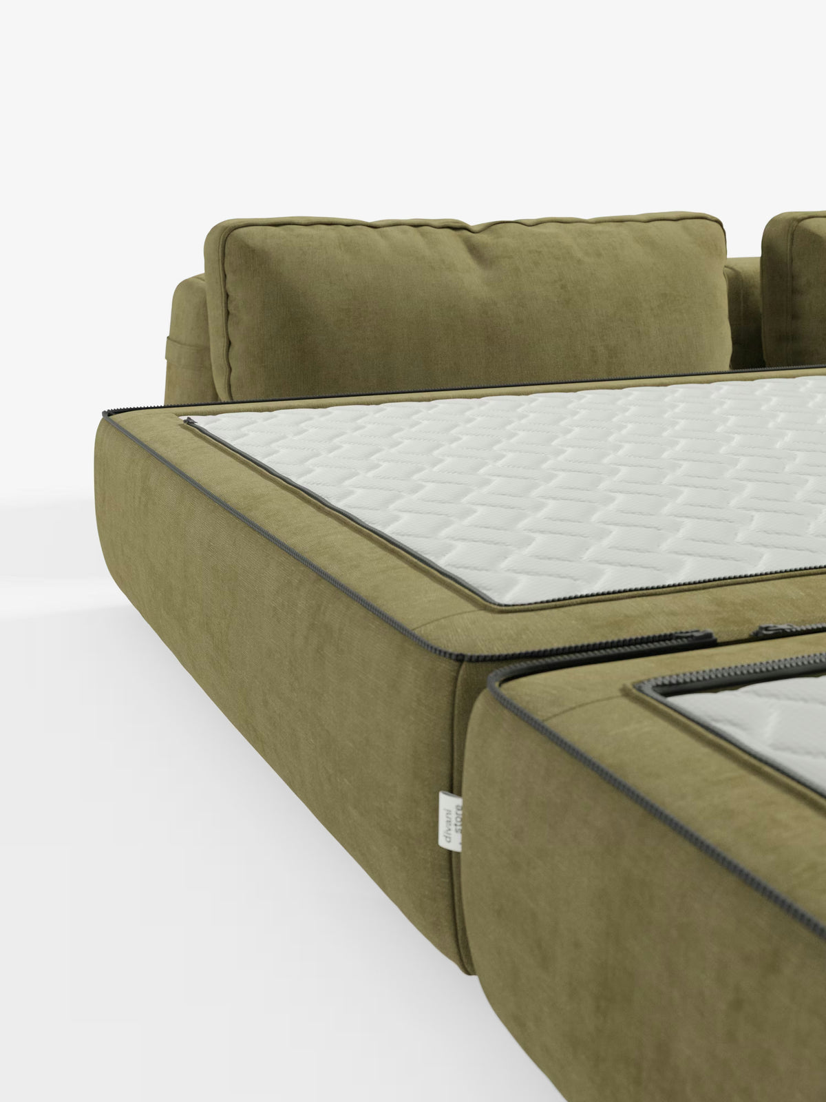 Primo piano di un divano letto matrimoniale a 2 posti “Rift” color verde oliva di Divani.Store, caratterizzato da schienali mobili e da un cuscino di seduta rimovibile che rivela un materasso alto 24 cm in memory foam, rivestito in tessuto T31 lavabile con finitura trapuntata bianca. I cuscini presentano cuciture a vista e cerniere, mentre lo sfondo bianco a tinta unita mette in risalto la raffinata trama e la maestria artigianale di questo versatile divano letto.