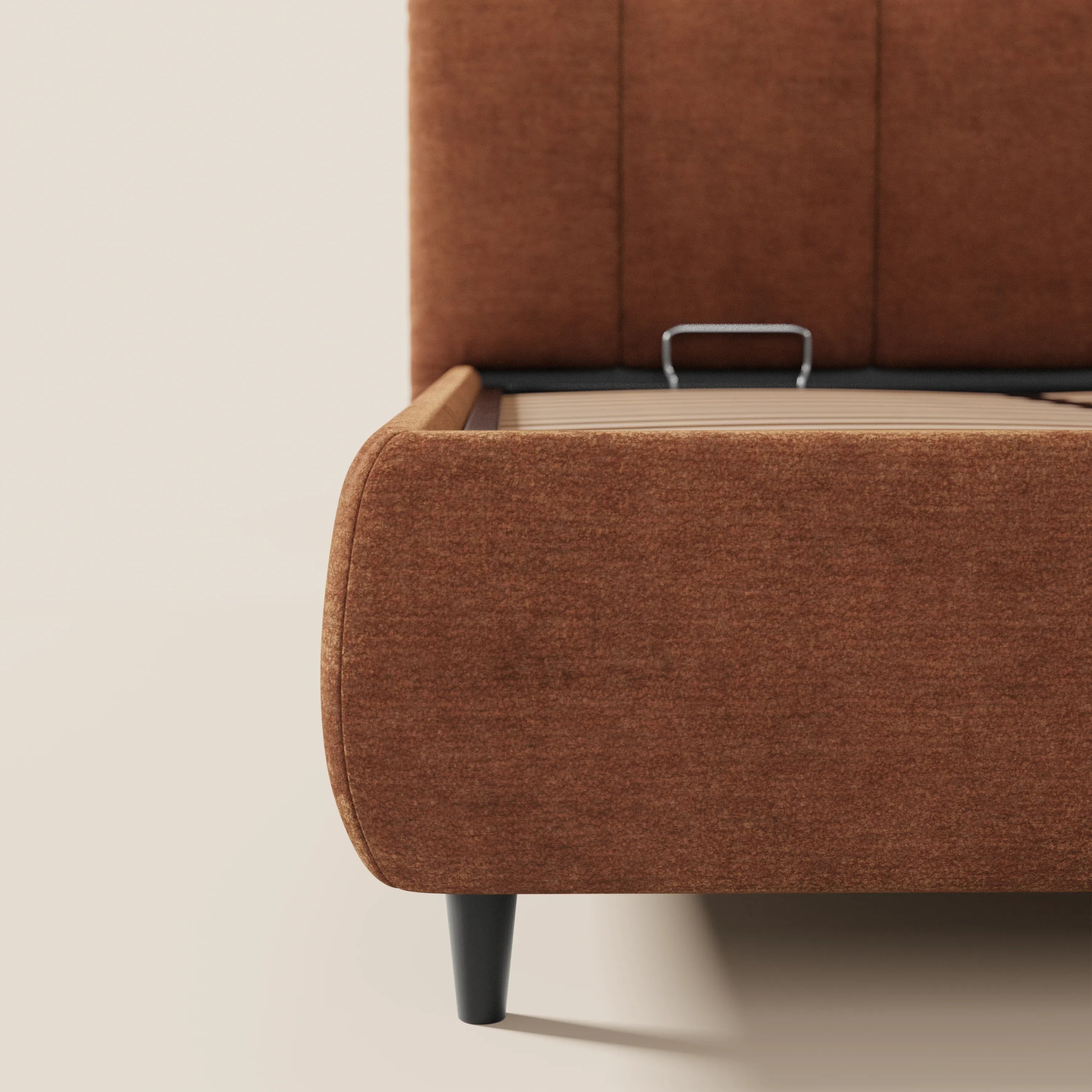 Un primo piano del letto imbottito ARKAM con contenitore e testiera a lavorazione verticale di Letti.store, in tessuto certificato Oeko-Tex®, con angoli arrotondati, gambe nere affusolate e cassetto sotto il letto aperto con maniglia metallica su sfondo neutro.
