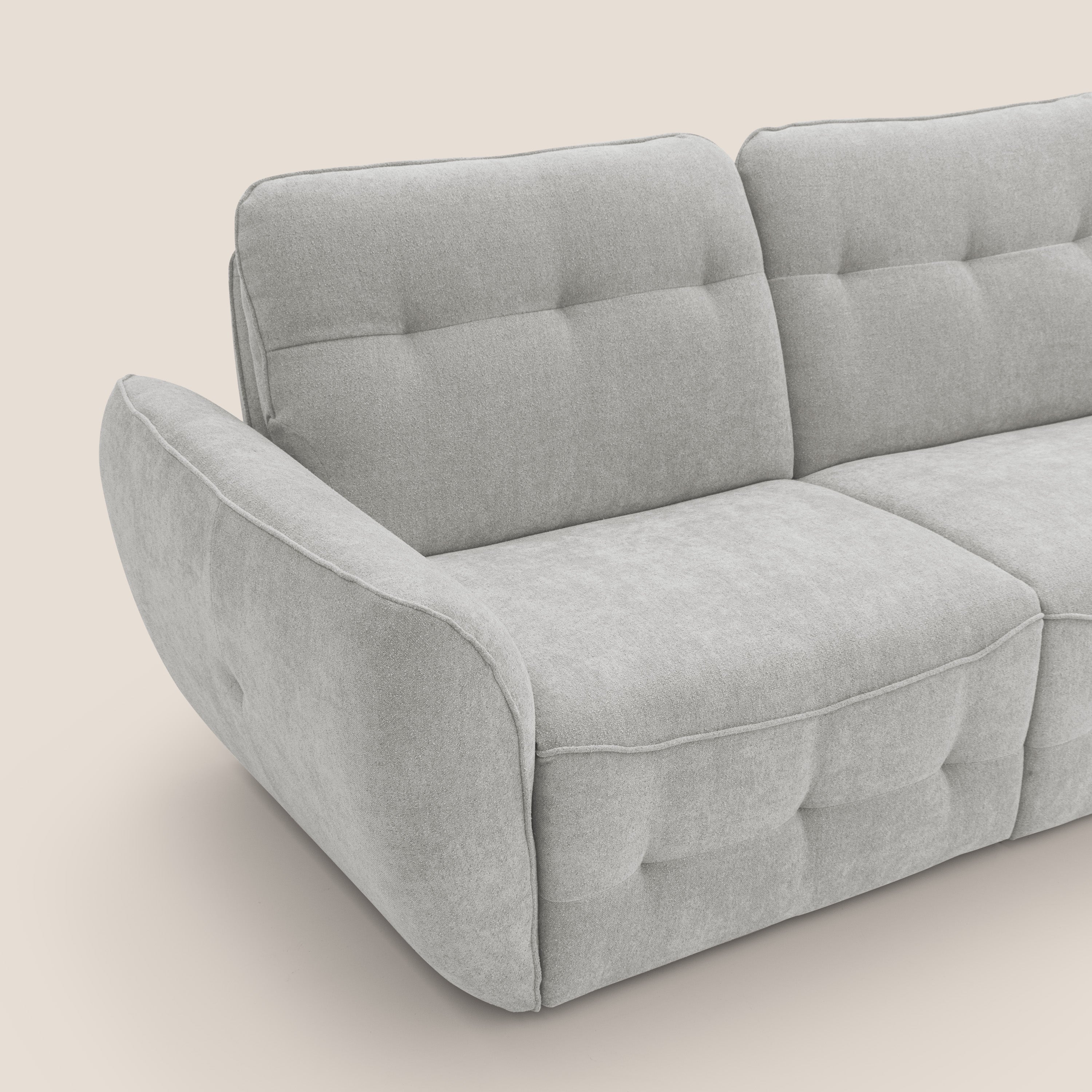 Il divano Cerbero 3 posti di Divani.Store (208 cm) in bouclé impermeabile grigio chiaro T07 è caratterizzato da cuscini trapuntati e ampi braccioli arrotondati per un look accogliente. Solo una parte di questo divano moderno è mostrata su uno sfondo beige neutro.