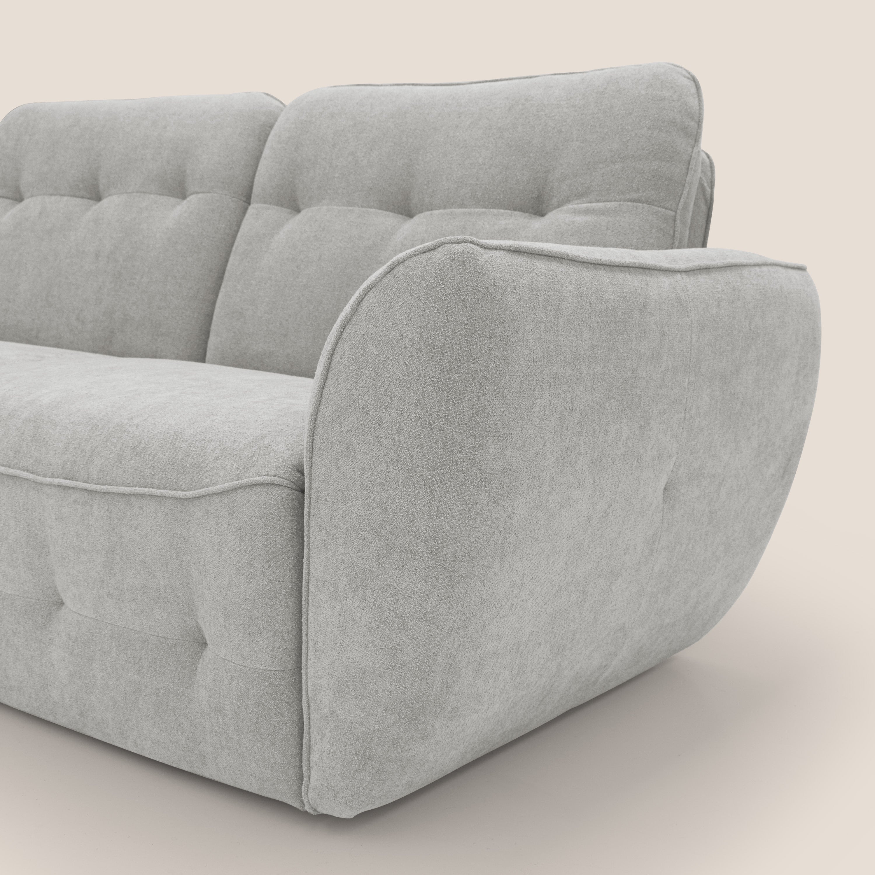 Primo piano del divano Cerbero 3 posti (208 cm) di Divani.Store, in morbido bouclé grigio chiaro T07, resistente all'acqua, con cuscini di seduta e di schienale in peluche e trapuntati, con bordi arrotondati su uno sfondo bianco sporco.