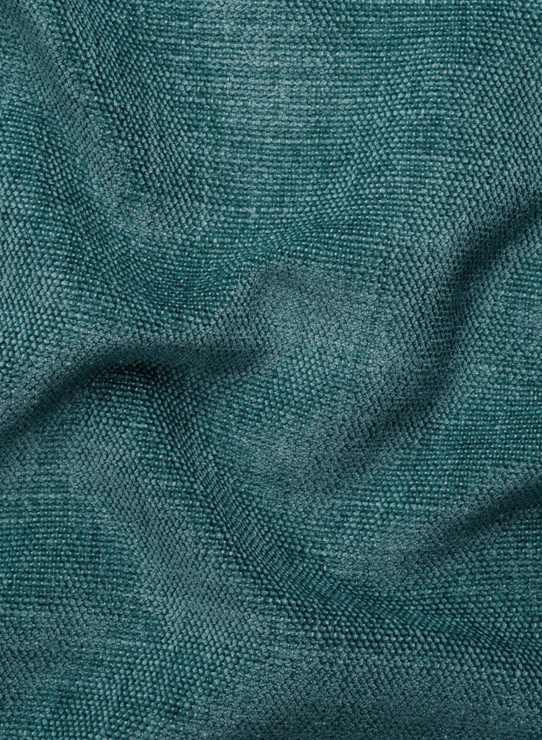 Un primo piano del tessuto color verde acqua dalla trama rigata, drappeggiato in morbide pieghe su un divano letto angolare Ischia con schienali traslanti, elemento estraibile e penisola contenitore in tessuto smacchiabile misto lino, caratterizzato da un motivo intrecciato fitto.