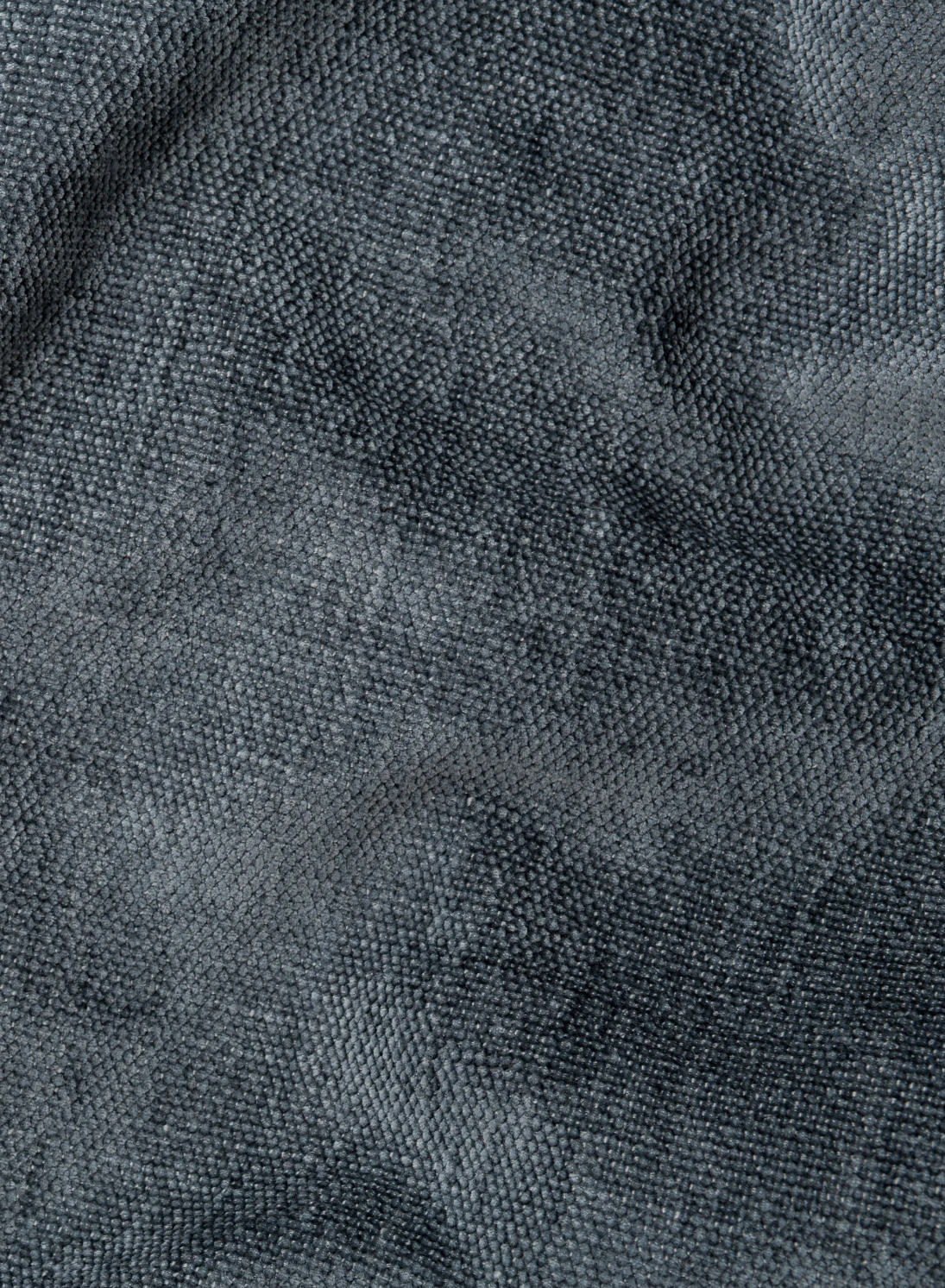 Primo piano del tessuto intrecciato grigio scuro del divano letto angolare Ischia, caratterizzato da un motivo a griglia fitto e uniforme con sottili giochi di luci e ombre che creano un effetto morbido e leggermente stropicciato.