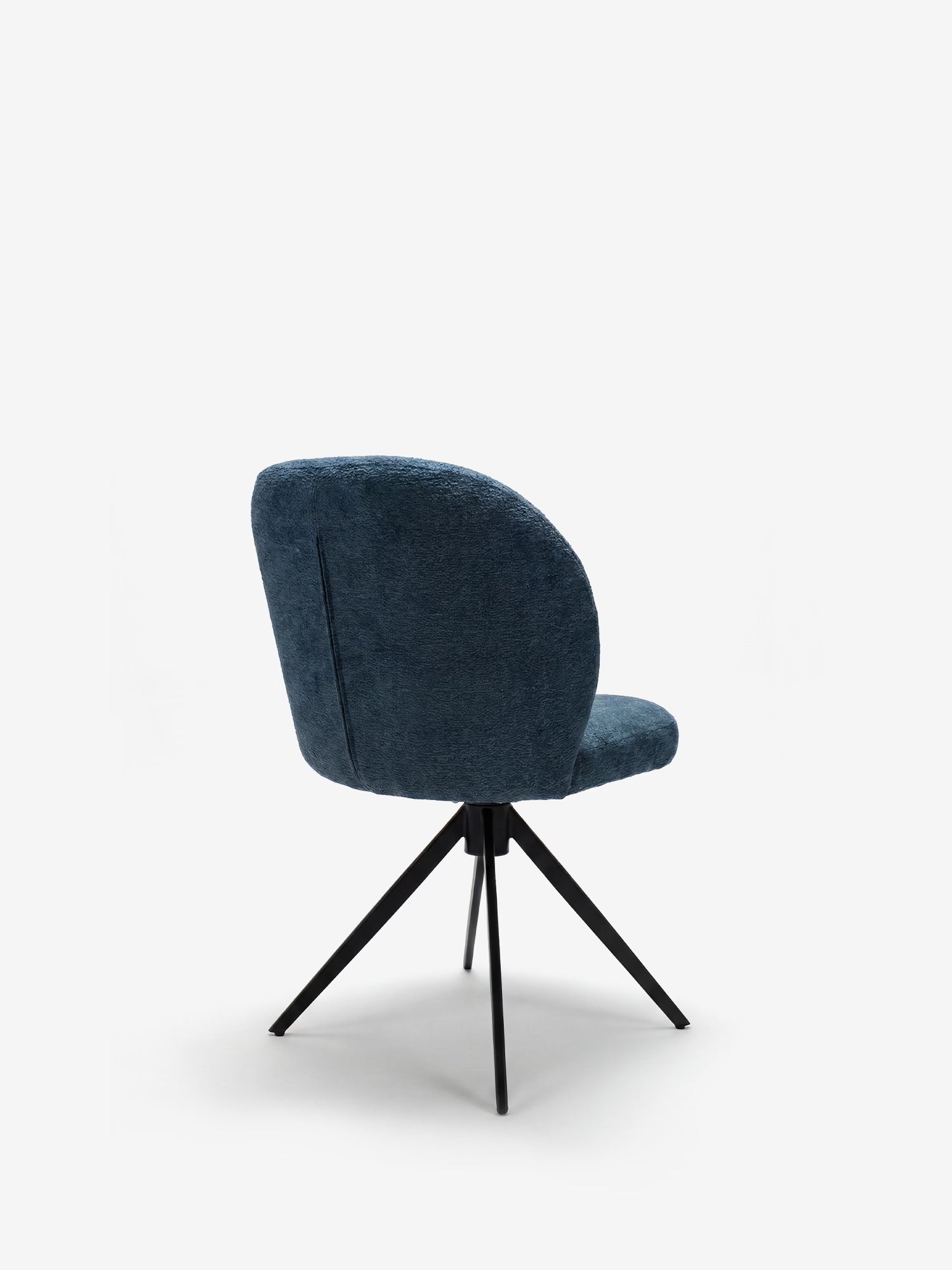 La sedia imbottita Alba di Divani.Store presenta uno schienale arrotondato e imbottito di colore blu e una seduta in tessuto effetto cotone certificato OEKO-TEX®, con quattro gambe angolate in metallo nero; nella foto è raffigurata vista da dietro su uno sfondo bianco a tinta unita.