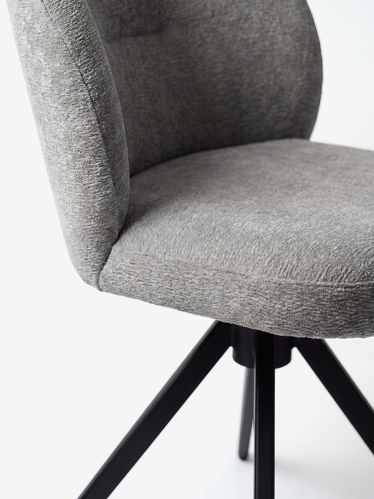 Primo piano della sedia imbottita Alba di Divani.Store, realizzata con tessuto effetto cotone certificato OEKO-TEX® in grigio e una robusta base in metallo nero. Il design minimalista risalta sullo sfondo bianco.