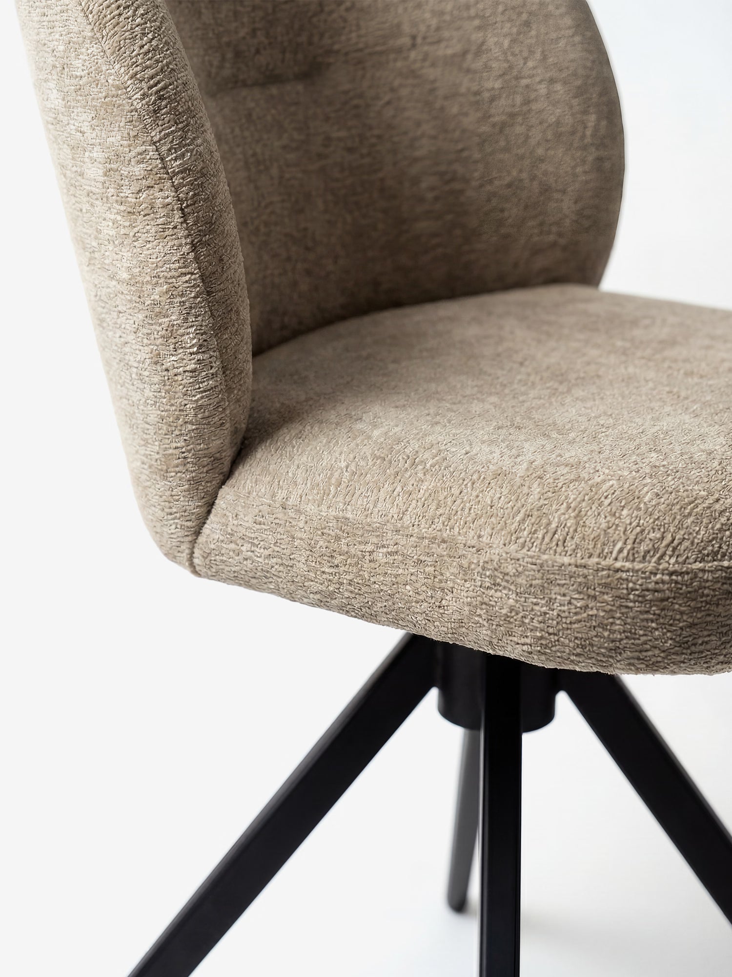 Un primo piano della sedia imbottita Alba in tessuto effetto cotone certificato OEKO-TEX® di Divani.Store ne mette in risalto il rivestimento beige, la seduta e lo schienale curvi, oltre alla base in metallo nero, il tutto su uno sfondo bianco a tinta unita.