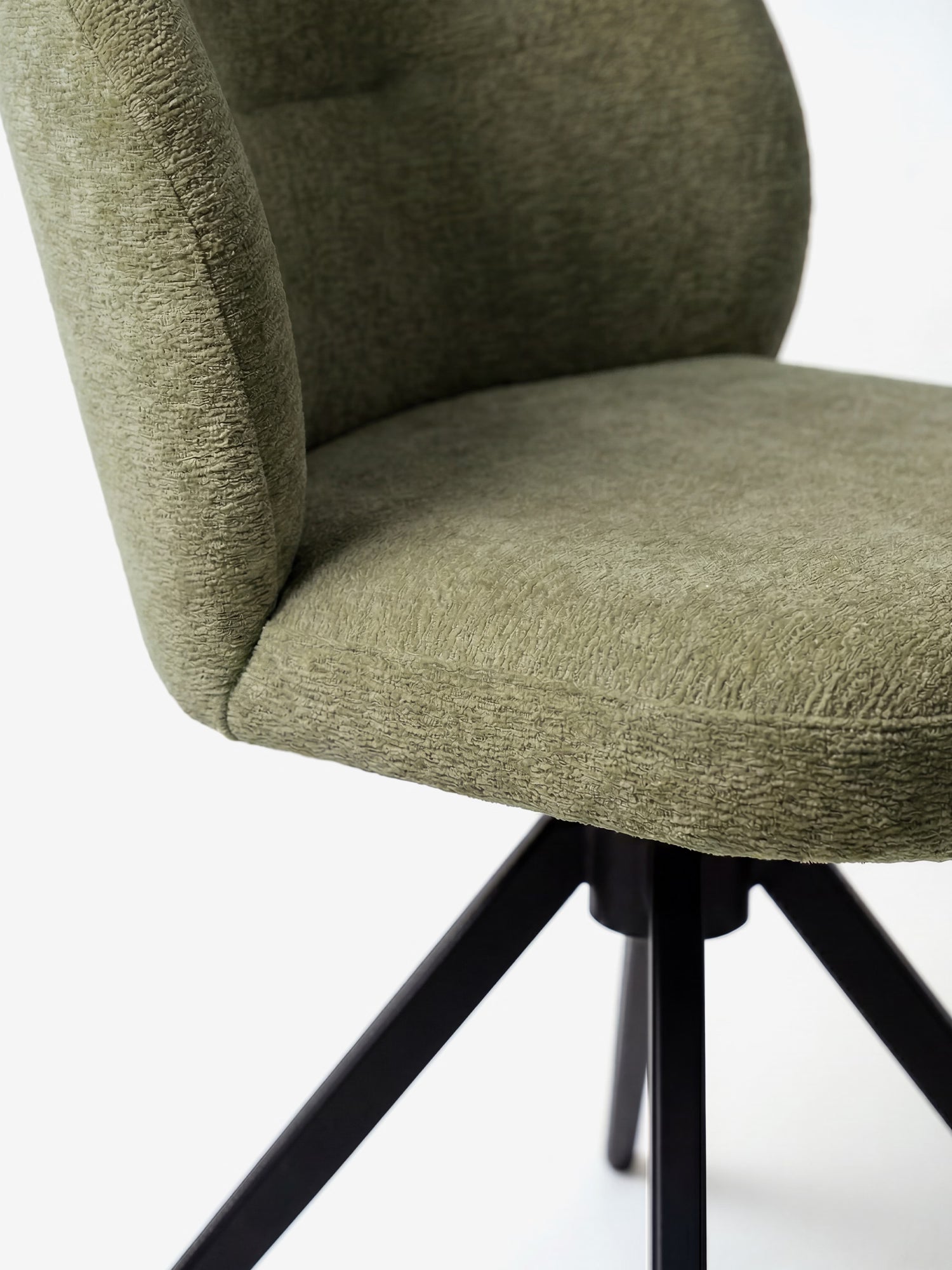 Primo piano della sedia Alba di Divani.Store, una sedia imbottita in tessuto effetto cotone certificato OEKO-TEX® (verde oliva) con schienale leggermente ricurvo e base a quattro razze in metallo nero, raffigurata su uno sfondo bianco a tinta unita.