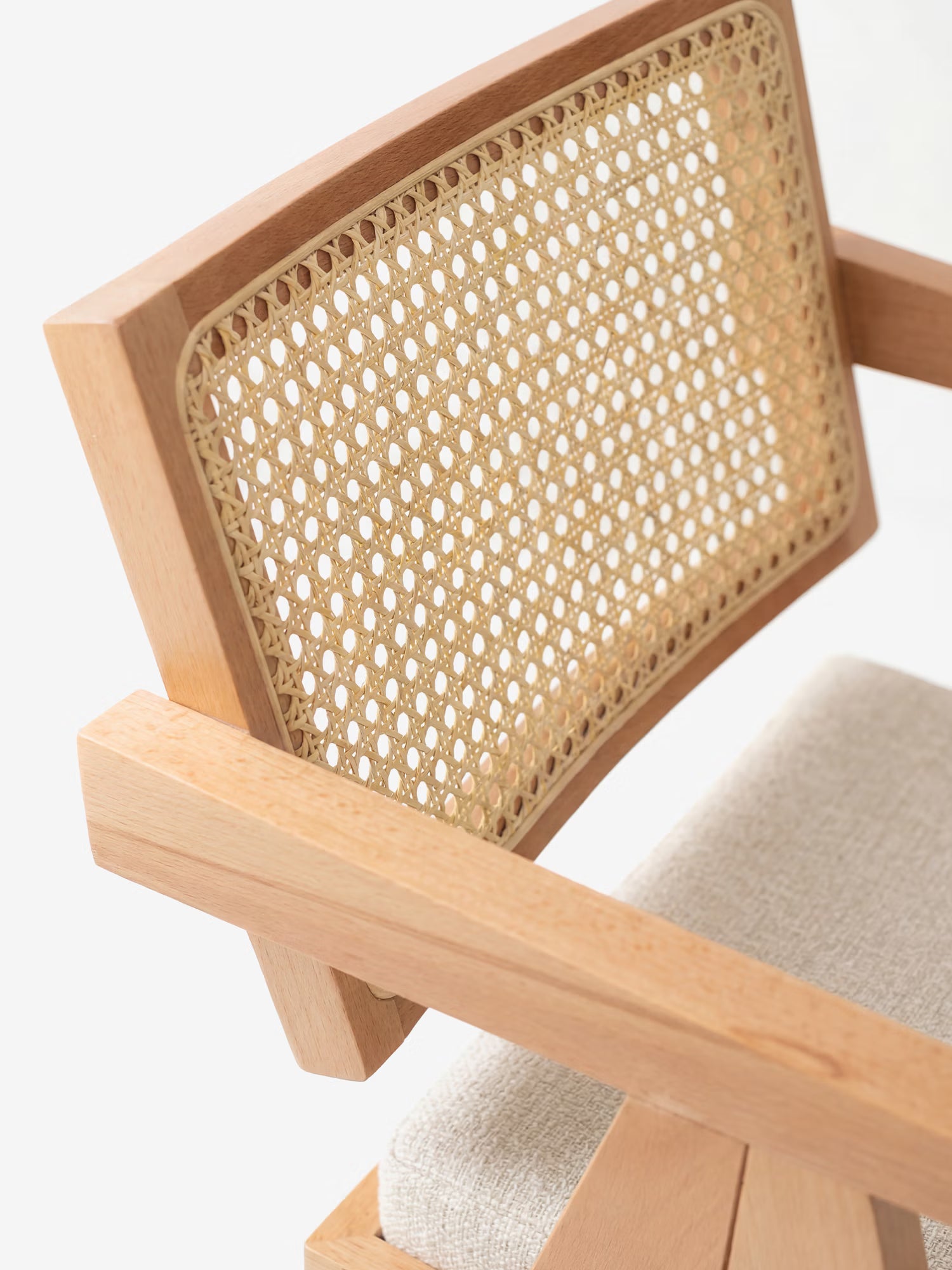 Primo piano della sedia Antea con braccioli in rovere di Divani.Store, caratterizzata da uno schienale in rattan e da una seduta imbottita rivestita in tessuto misto cotone. Questa sedia moderna presenta un design minimalista e una struttura in rovere chiaro.