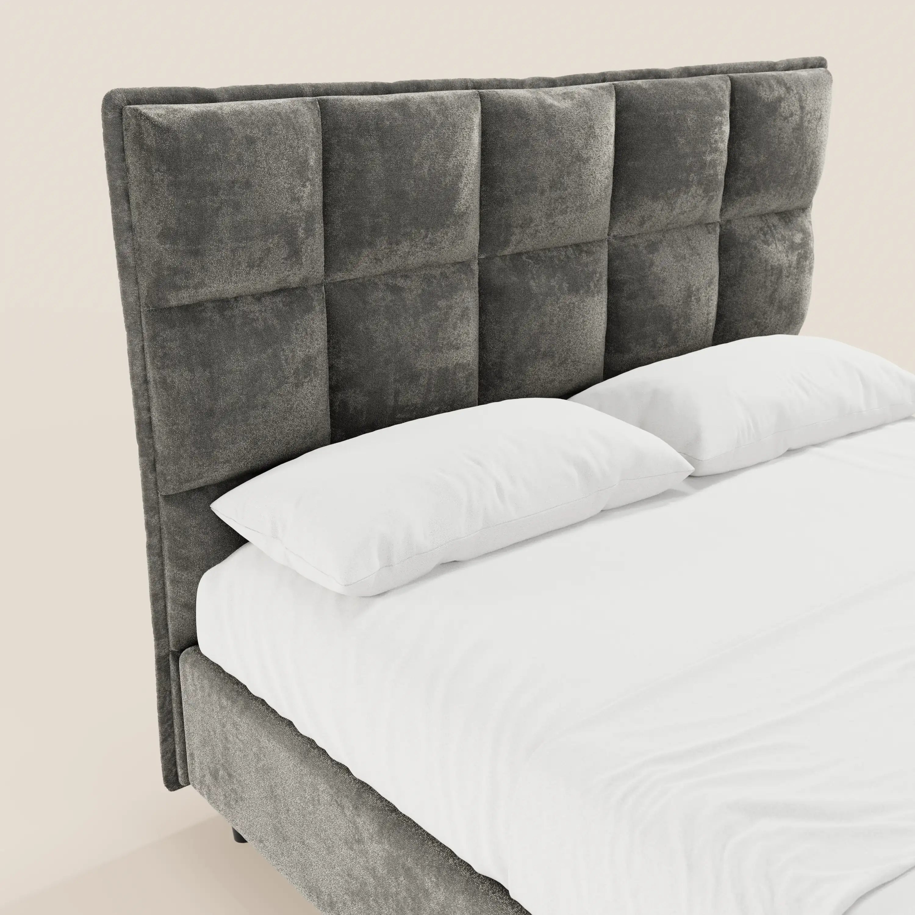 Il letto imbottito AURO di Letti.store presenta una testiera alta, in ciniglia certificata Oeko-Tex®, con lavorazione capitonné e ampi pannelli quadrati. Questo letto moderno è rifinito con cura con lenzuola e cuscini bianchi, che risaltano su uno sfondo beige a tinta unita.